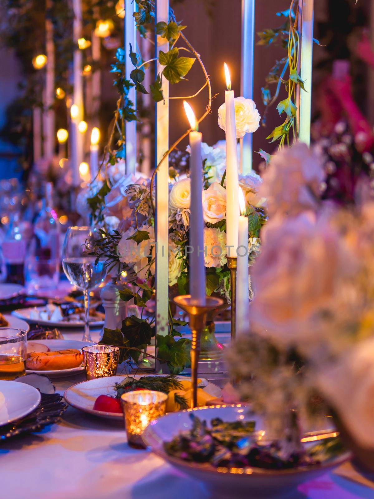 Table served for banquet with candles and floral compositions. Beautiful decorations in blue electric light. by aksenovko