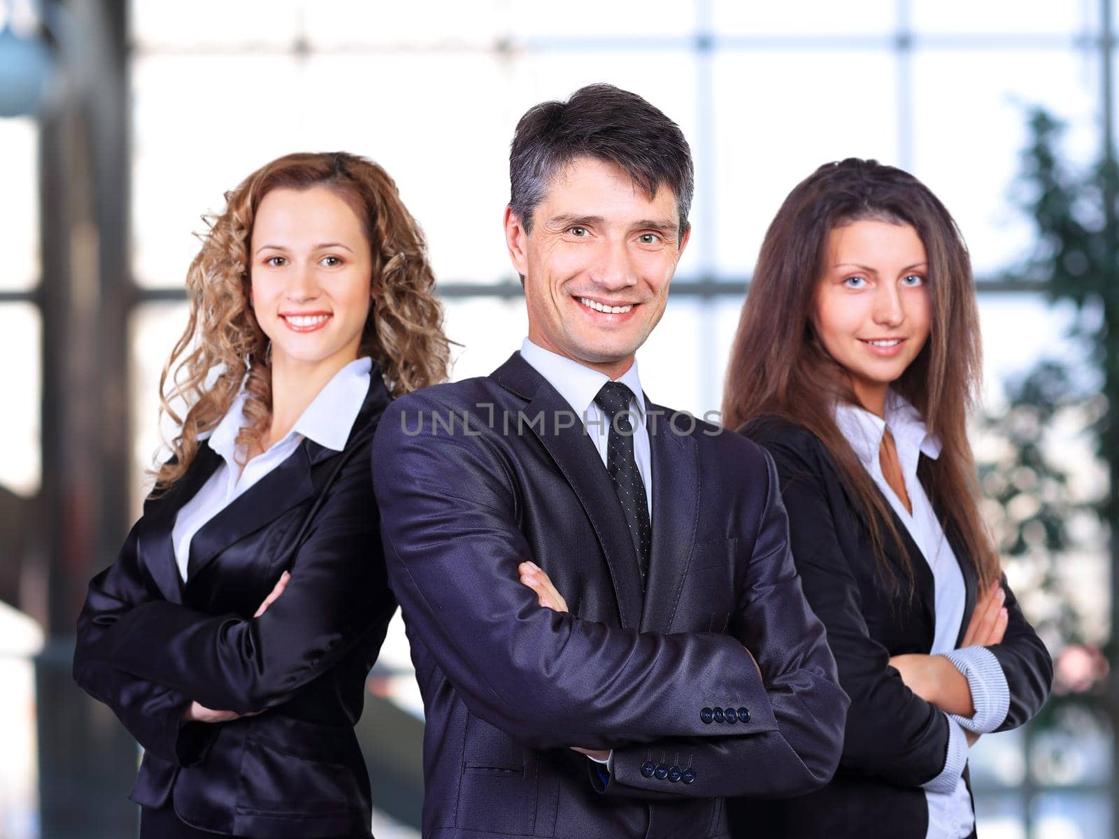 A business team with pretty leader in front looking at camera and smiling