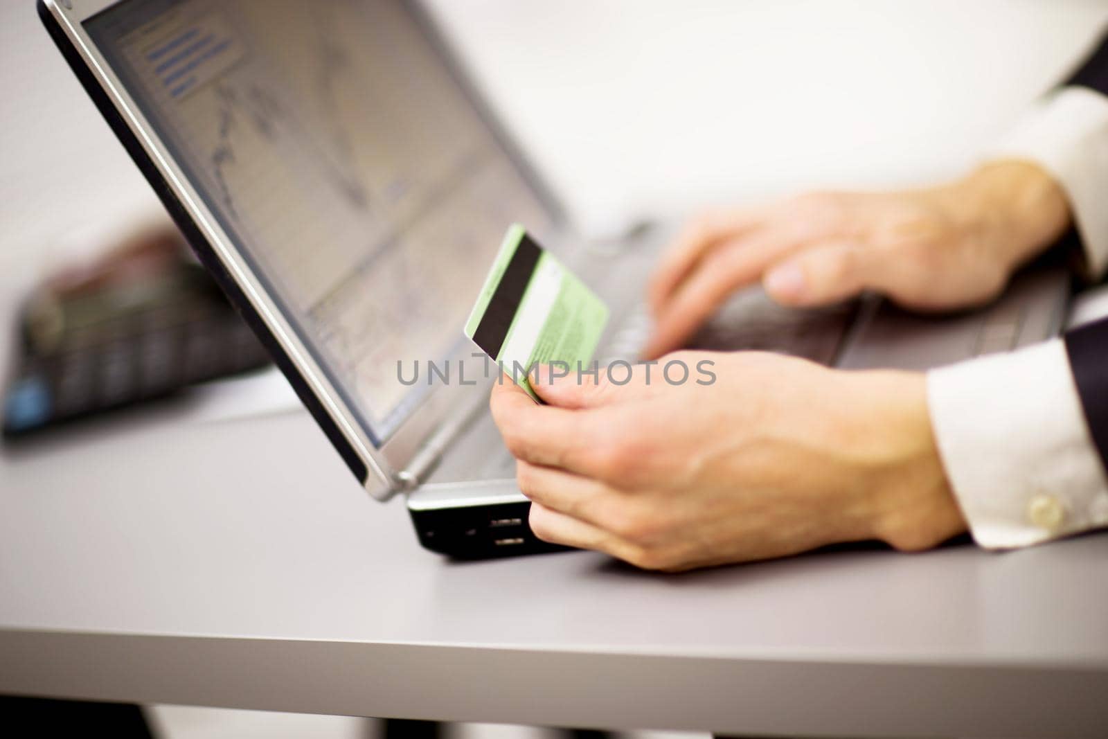 Young businessman holding a credit card and typing. On-line shopping on the internet using a laptop