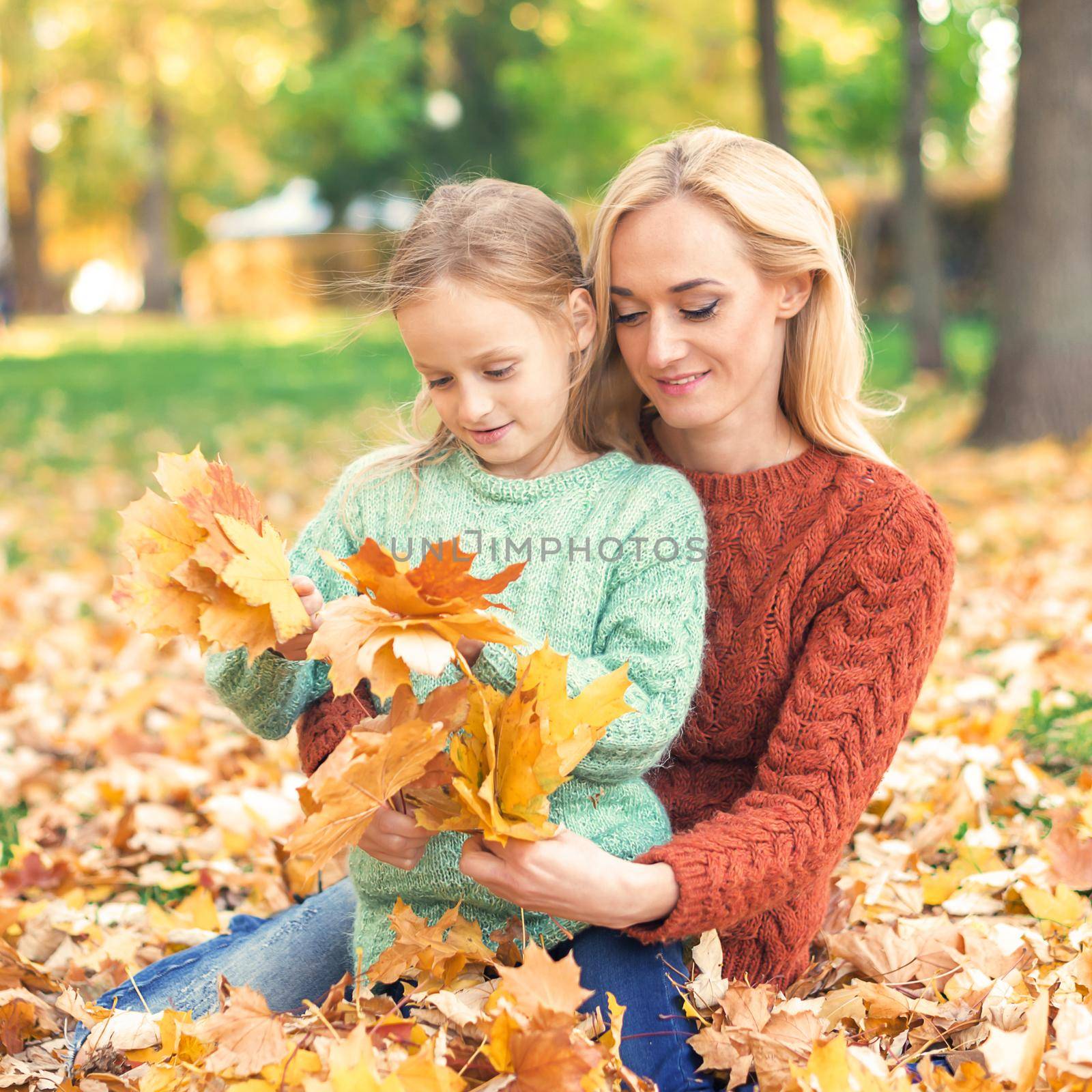 Woman and girl holding autumn yellow leaves by okskukuruza