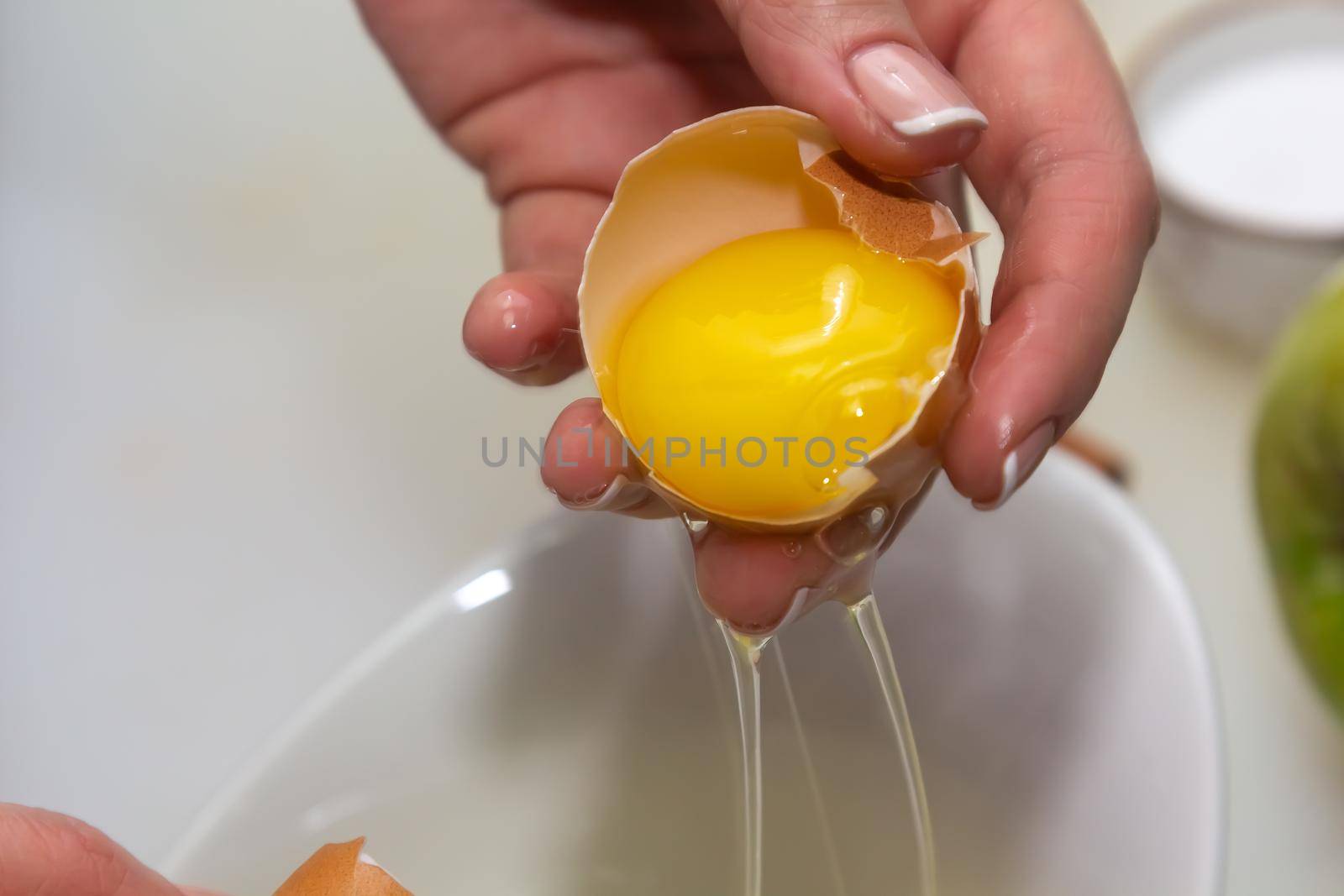 Hands holding egg shell with egg yolk separated by Milanchikov