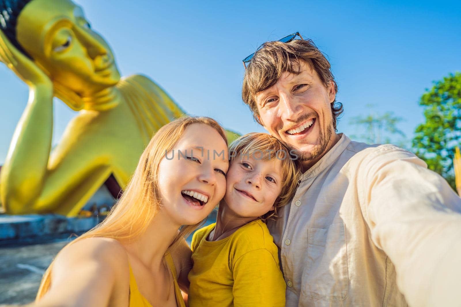 Coronavirus is over. Quarantine weakened. Take off the mask. Now you can travel. Happy tourists mother, father and son on background ofLying Buddha statue by galitskaya