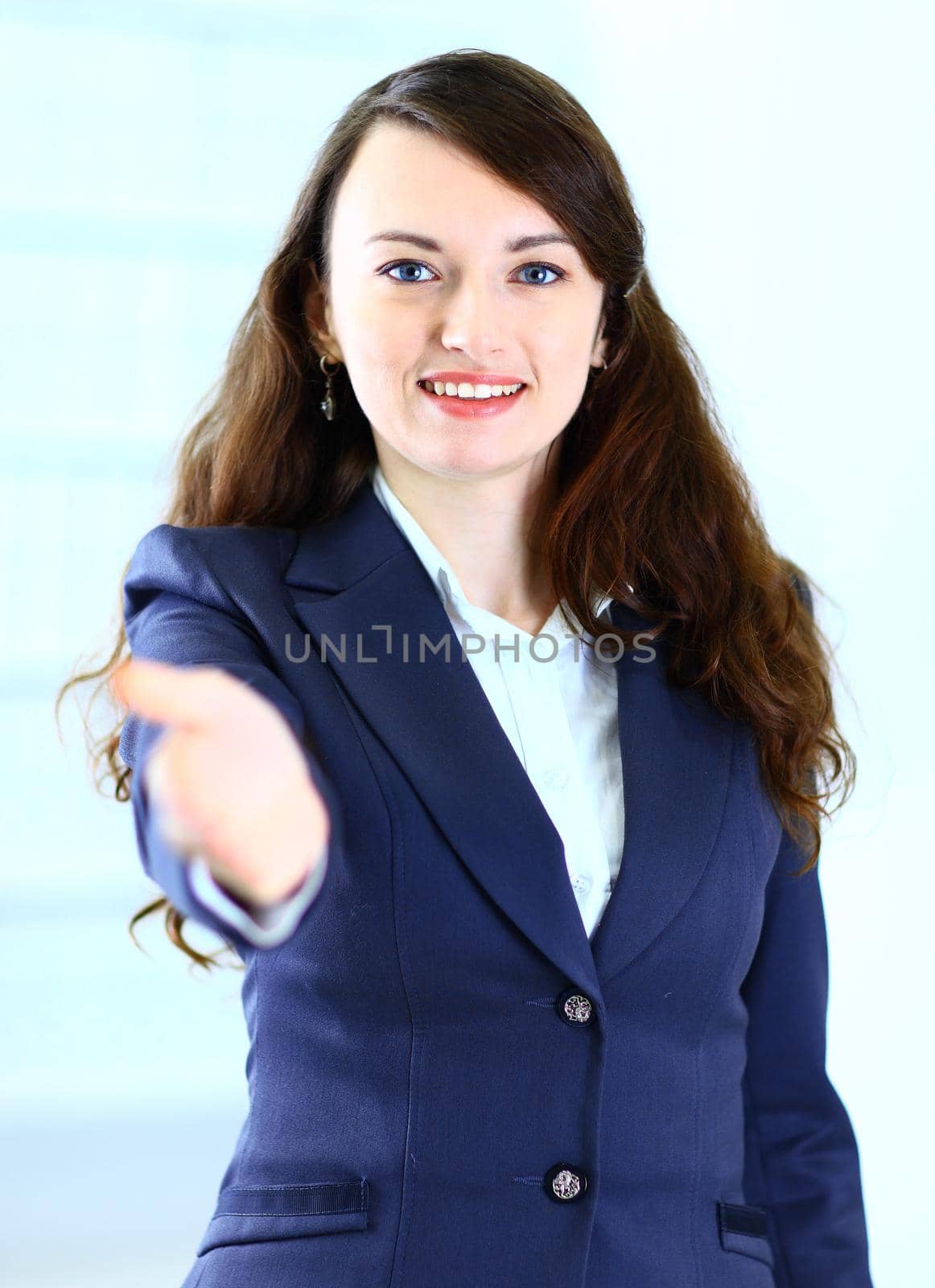 A beautiful young smiling business woman, happy and smiling , with an open hand ready to seal a deal or saying welcome. Isolated on a white background.
