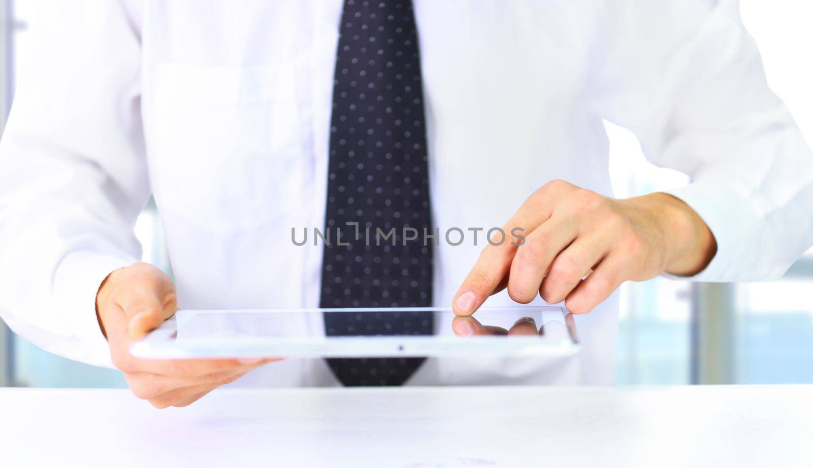 Casual businessman reading on tablet pc at the office