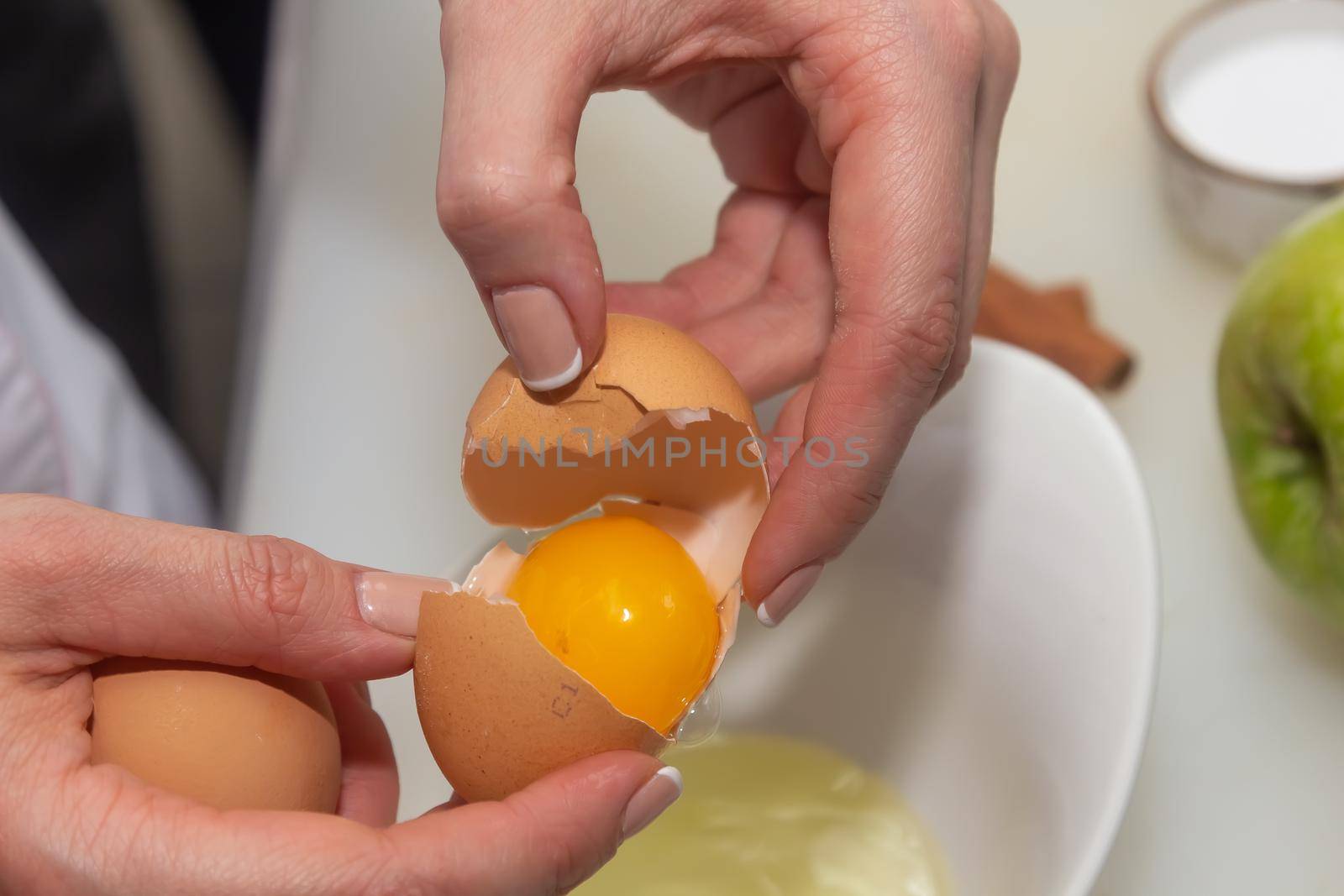 Hands holding egg shell with egg yolk separated.
