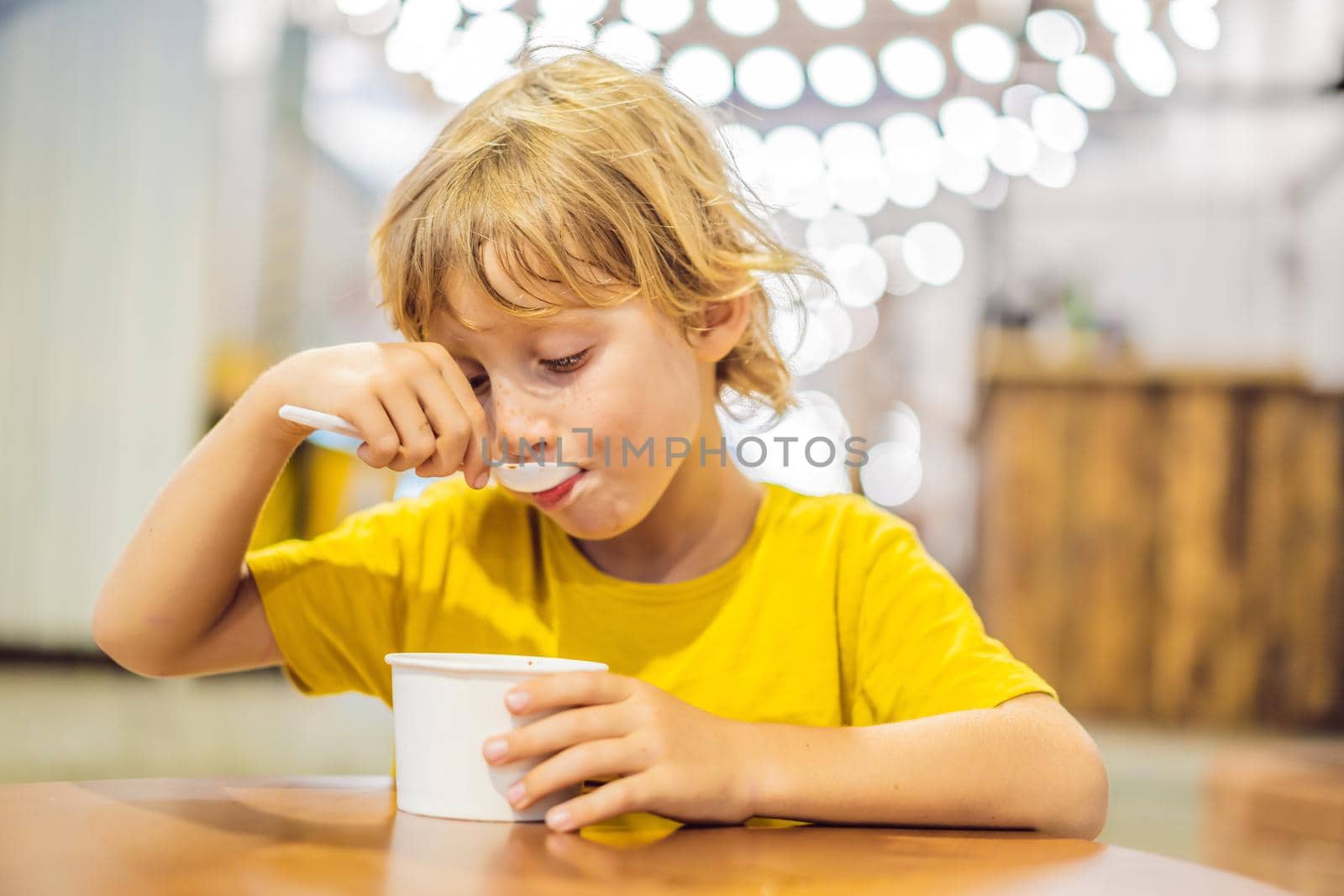 Coronavirus is over. Quarantine weakened. Take off the mask. Now you can go to public places. Boy eating ice cream in a cafe by galitskaya