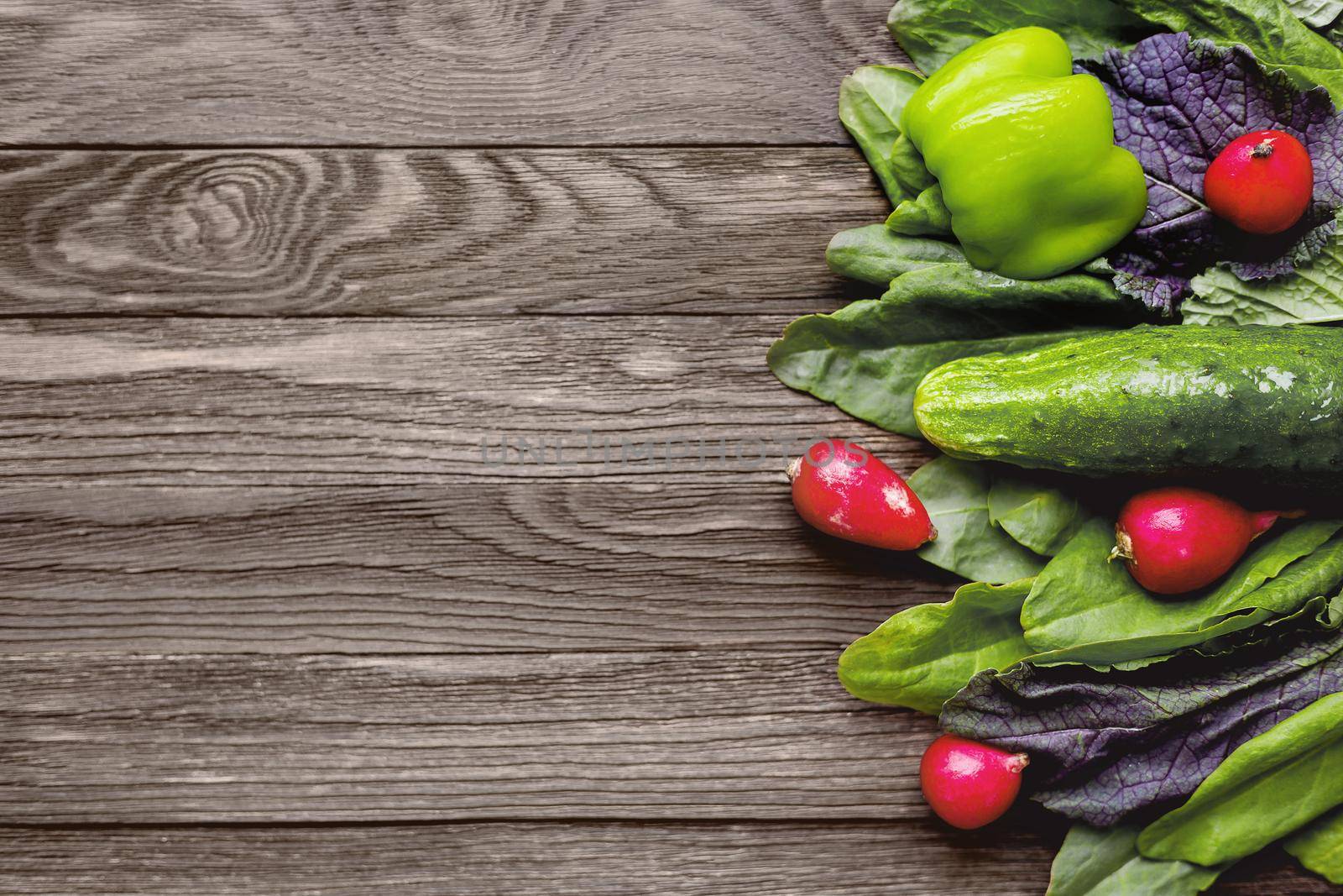 Fresh ingredients for salad - sorrel leaves, radishes, cucumber, sweet pepper on wooden background. Rustic table with tasty vegetables. Place for text. by aksenovko