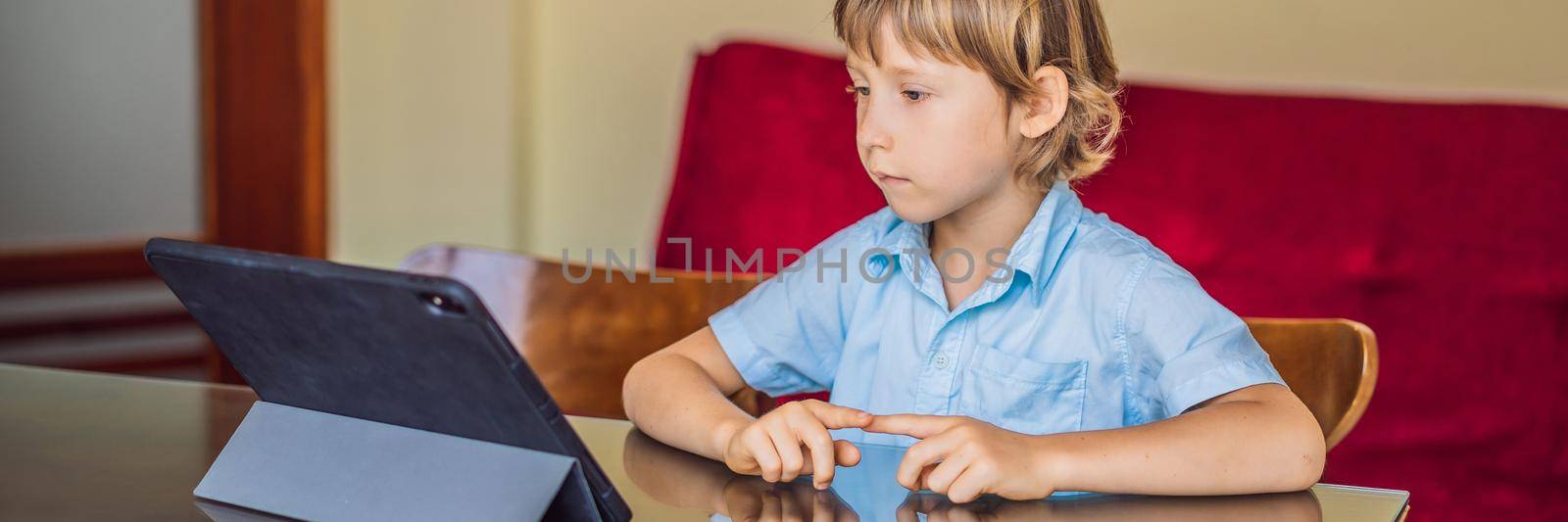 Boy studying online at home using tablet. Studying during quarantine. Global pandemic covid19 virus BANNER, LONG FORMAT by galitskaya