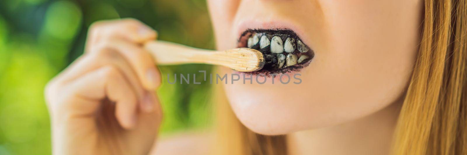 Young woman brush teeth using Activated charcoal powder for brushing and whitening teeth. Bamboo eco brush. BANNER, LONG FORMAT