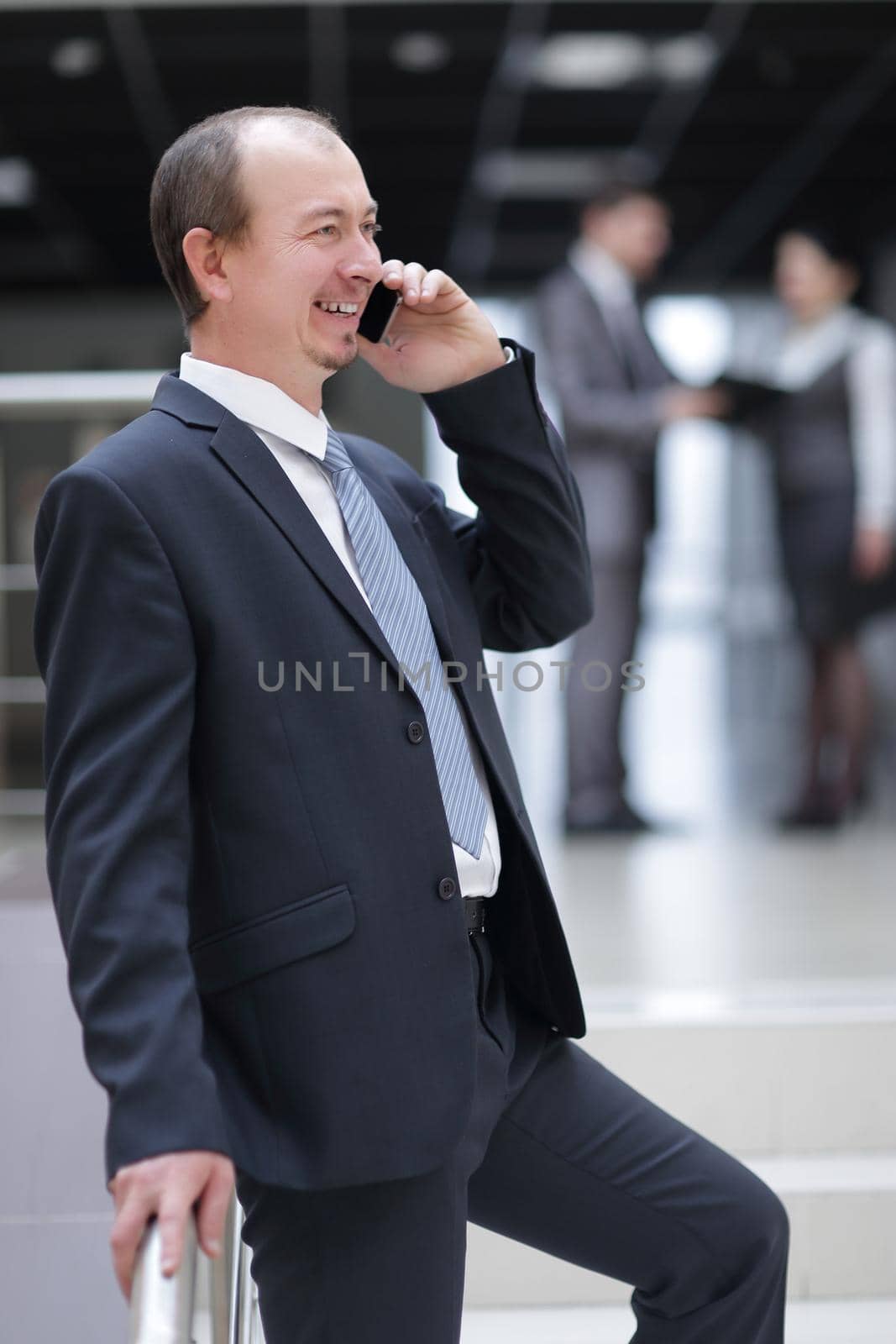 smiling businessman talking on mobile phone in office by SmartPhotoLab