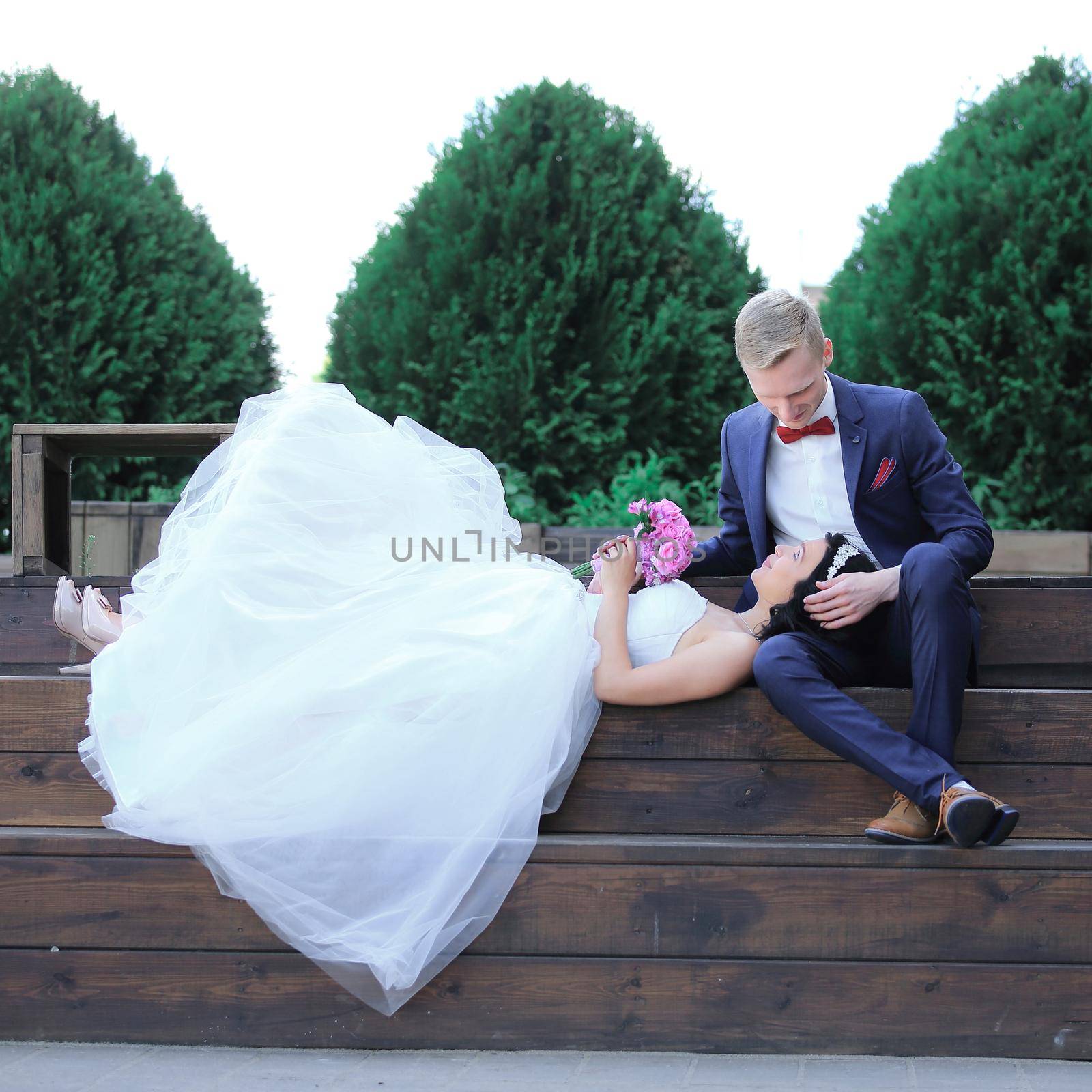 bride and groom resting on a wooden podium in the city Park.