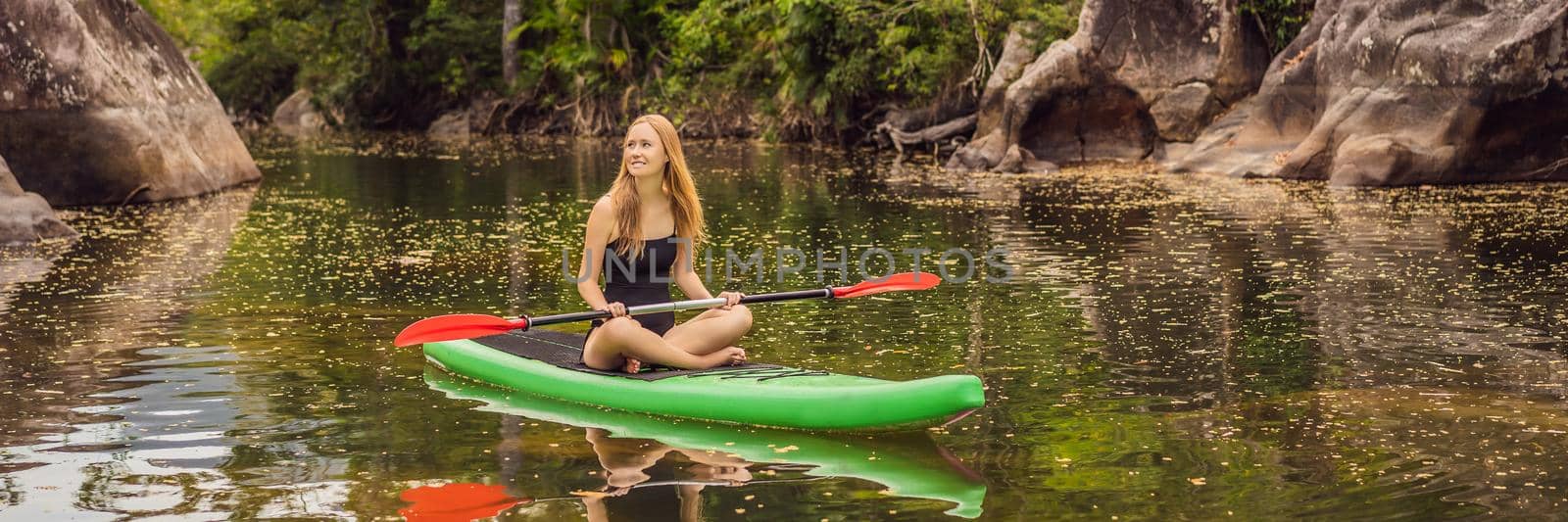 SUP Stand up paddle board woman paddle boarding on lake standing happy on paddleboard on blue water.Action Shot of Young Woman on Paddle Board. BANNER, LONG FORMAT