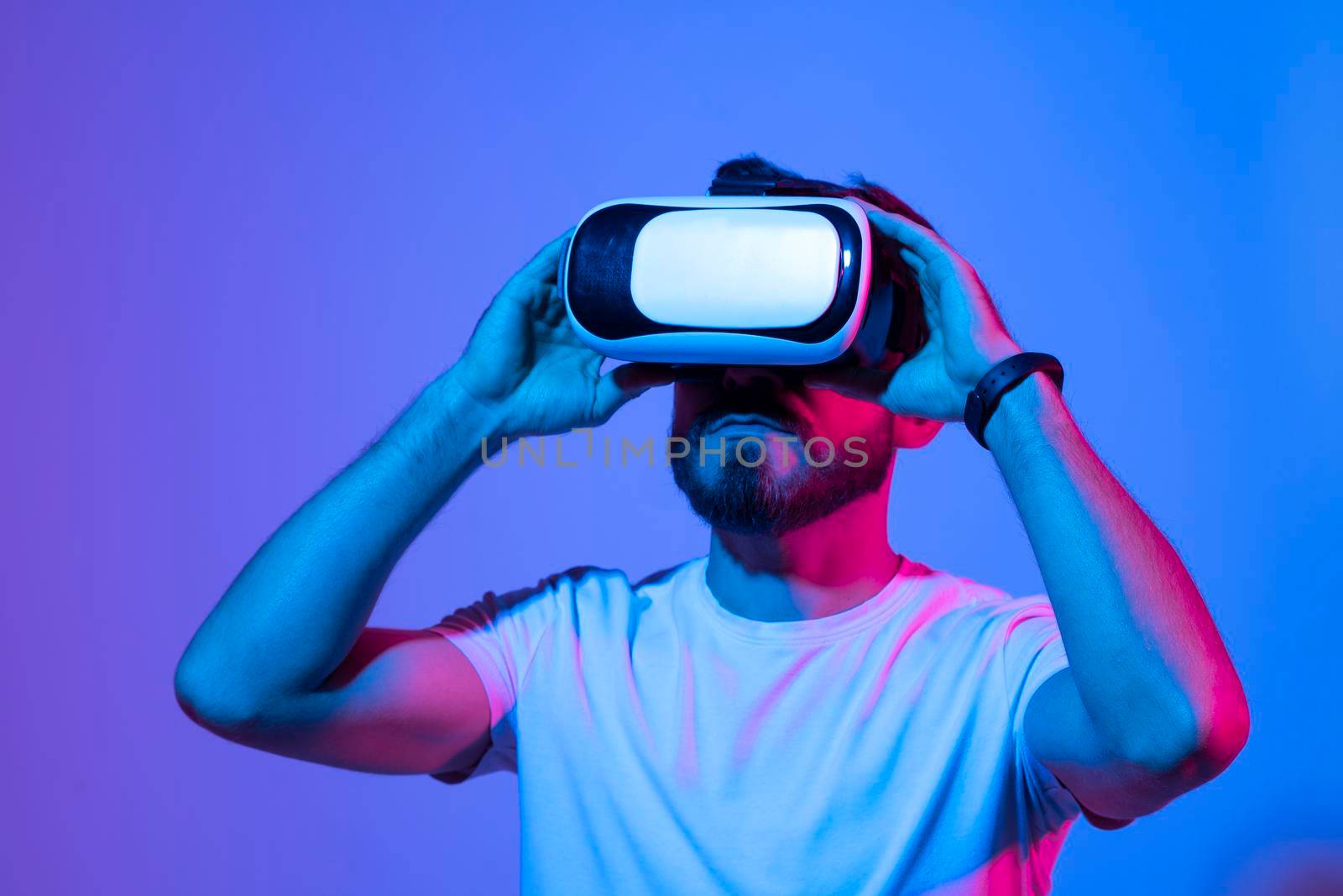 Metaverse concept. European young man in vr glasses, playing video games with virtual reality headset, trying to touch something with hand. by vovsht