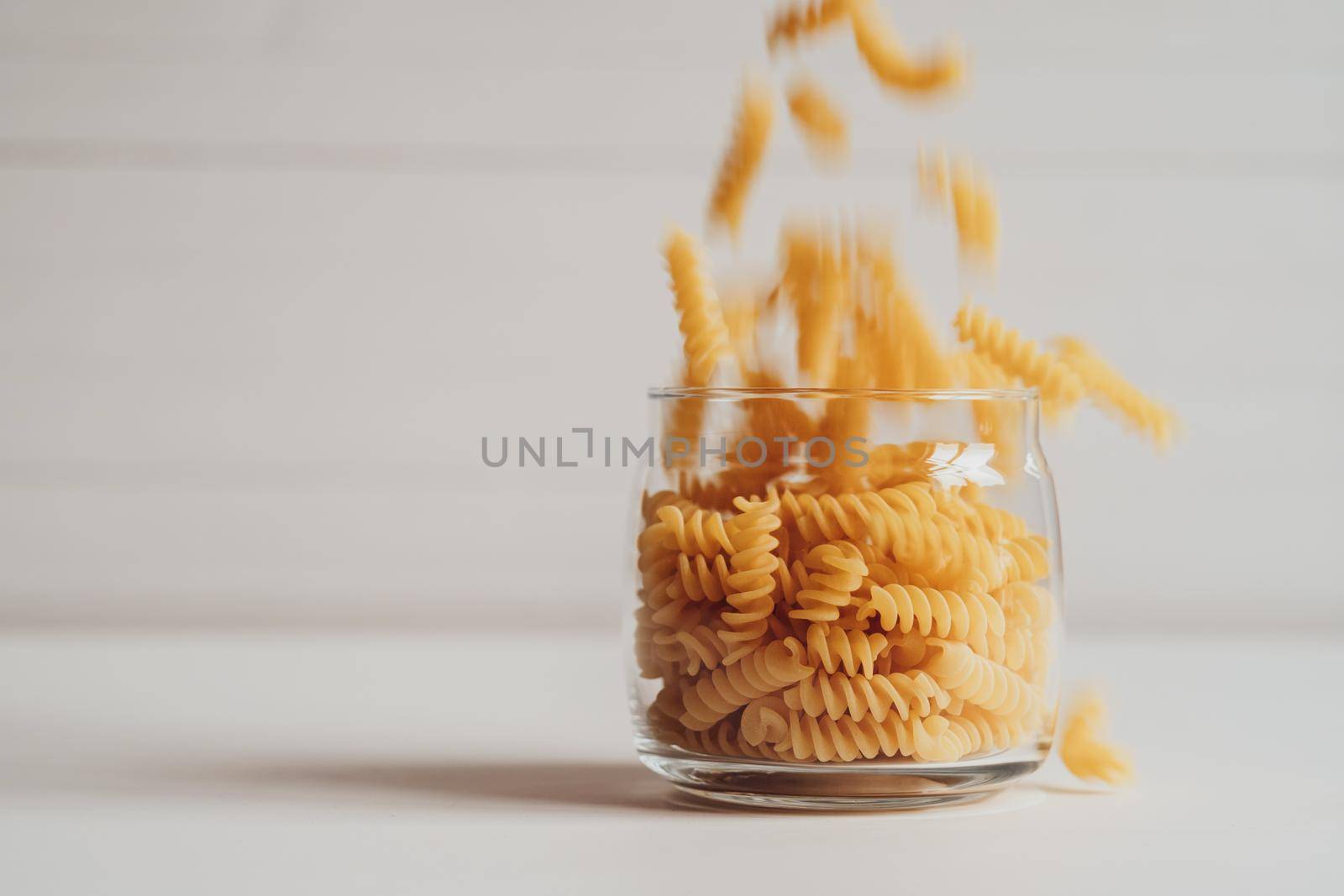 Pile of Wavy Pasta Dropped in Glass on White Background
