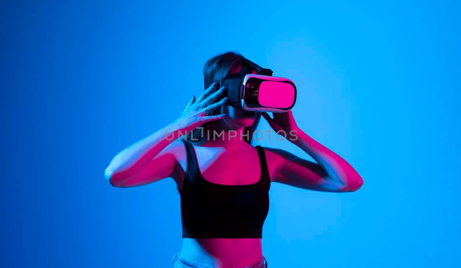 Smile happy woman getting experience using vr-headset glasses of virtual reality much gesticulating hands on gray background. Girl spend shes time in metaverse. by vovsht