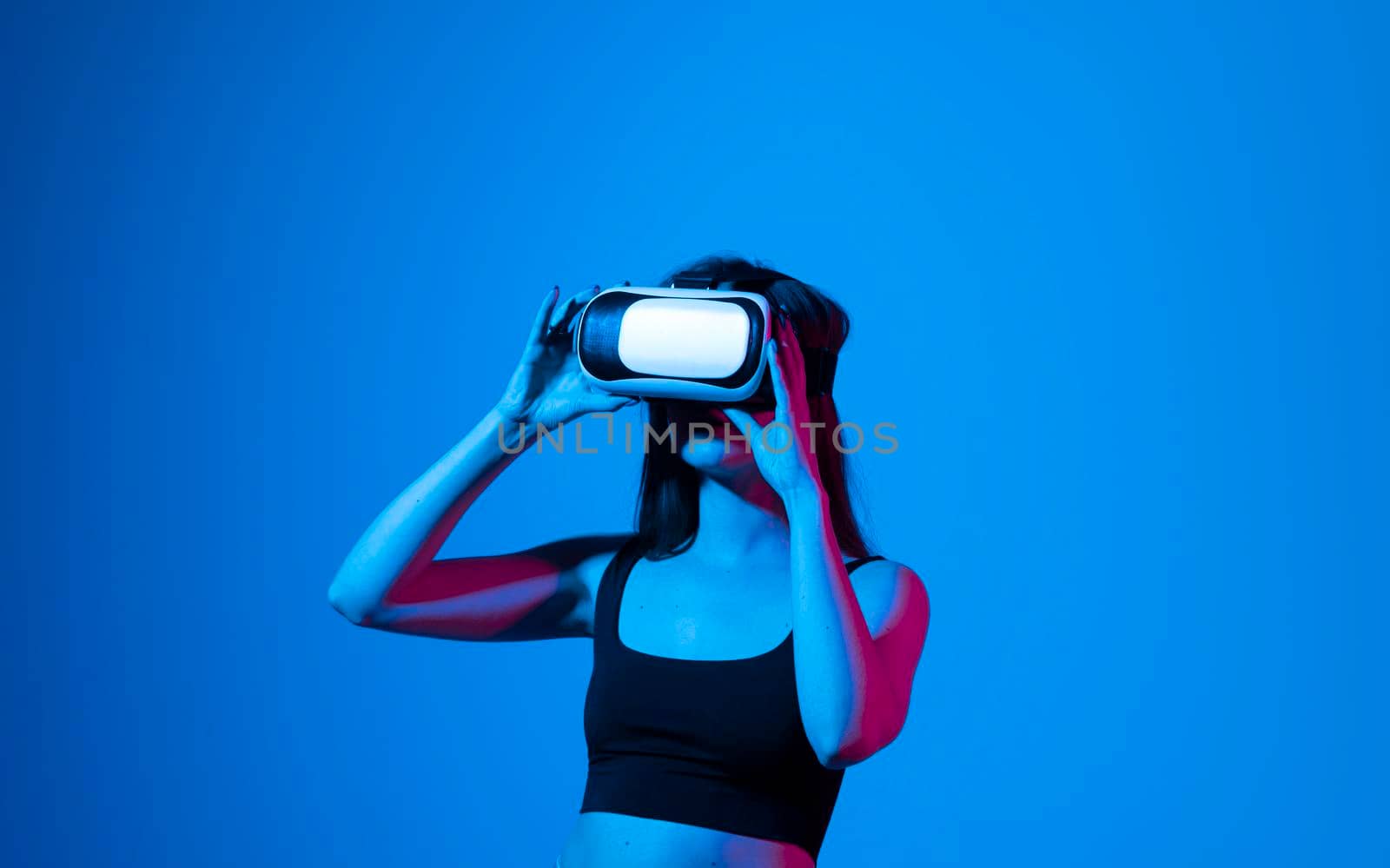 Smile happy woman getting experience using vr-headset glasses of virtual reality much gesticulating hands on gray background. Girl spend shes time in metaverse. by vovsht