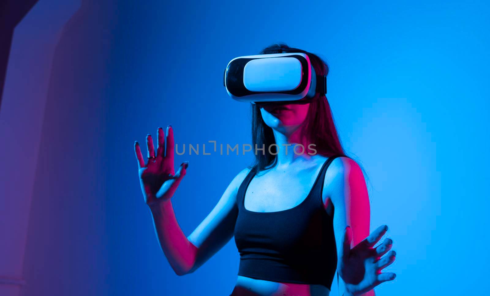 Young woman working in VR goggles on a grey background. Modern architect using virtual reality glasses at workplace. Designer working in augmented reality vr studio. by vovsht