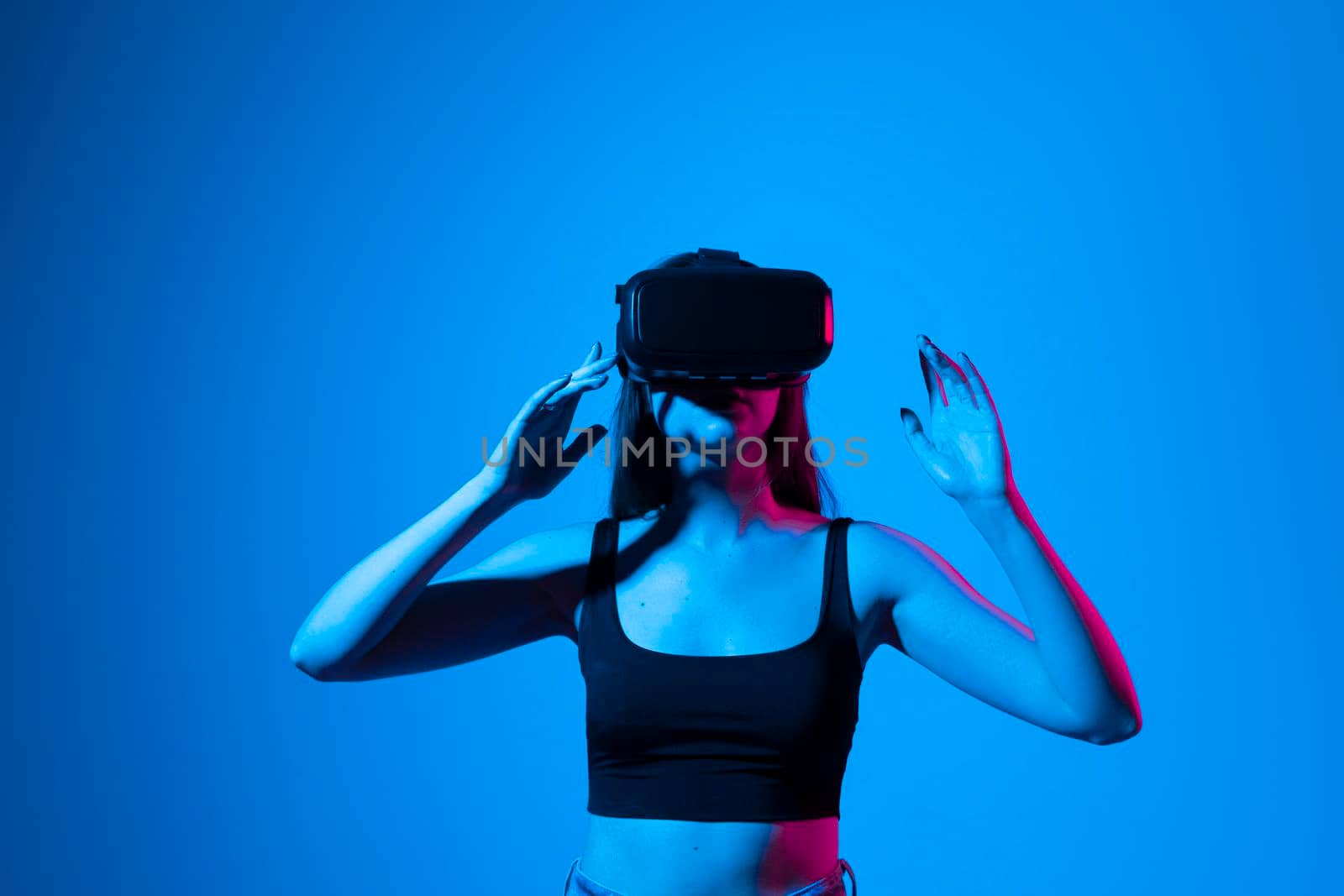 Young woman wearing VR goggles and interacts with cyberspace using swipe and stretching gestures while working on a project