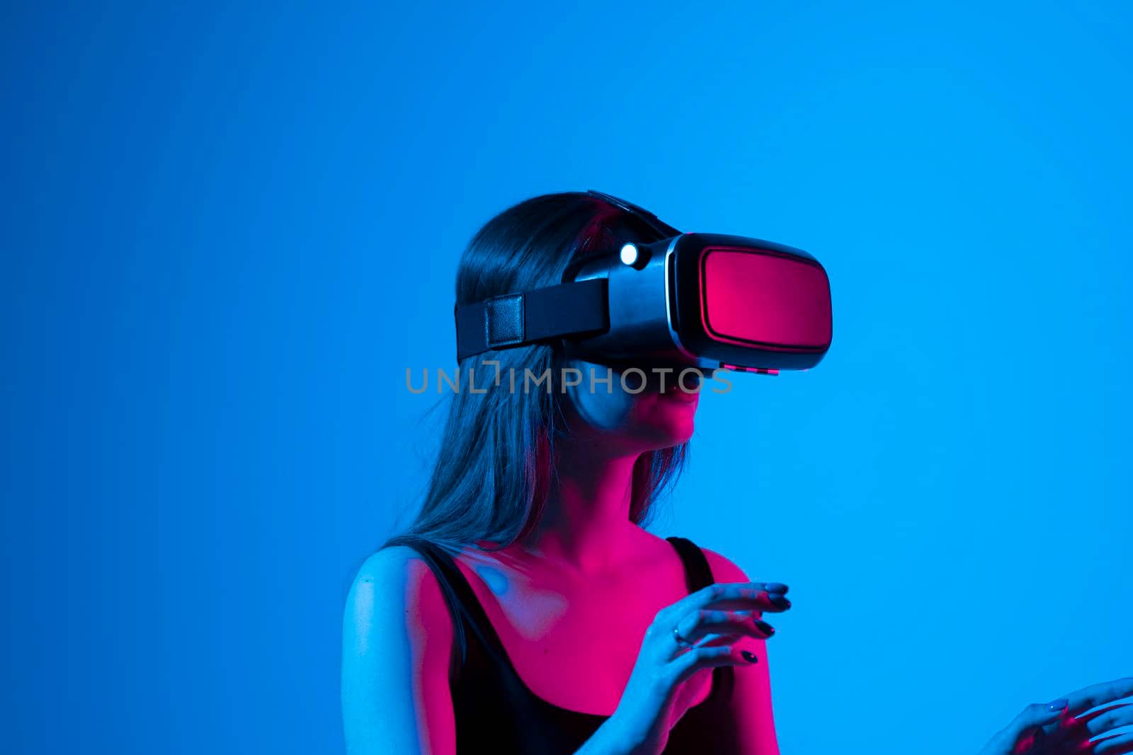 Smiling young woman using the VR goggles and communicating with friends in metaverse. Future technology concept