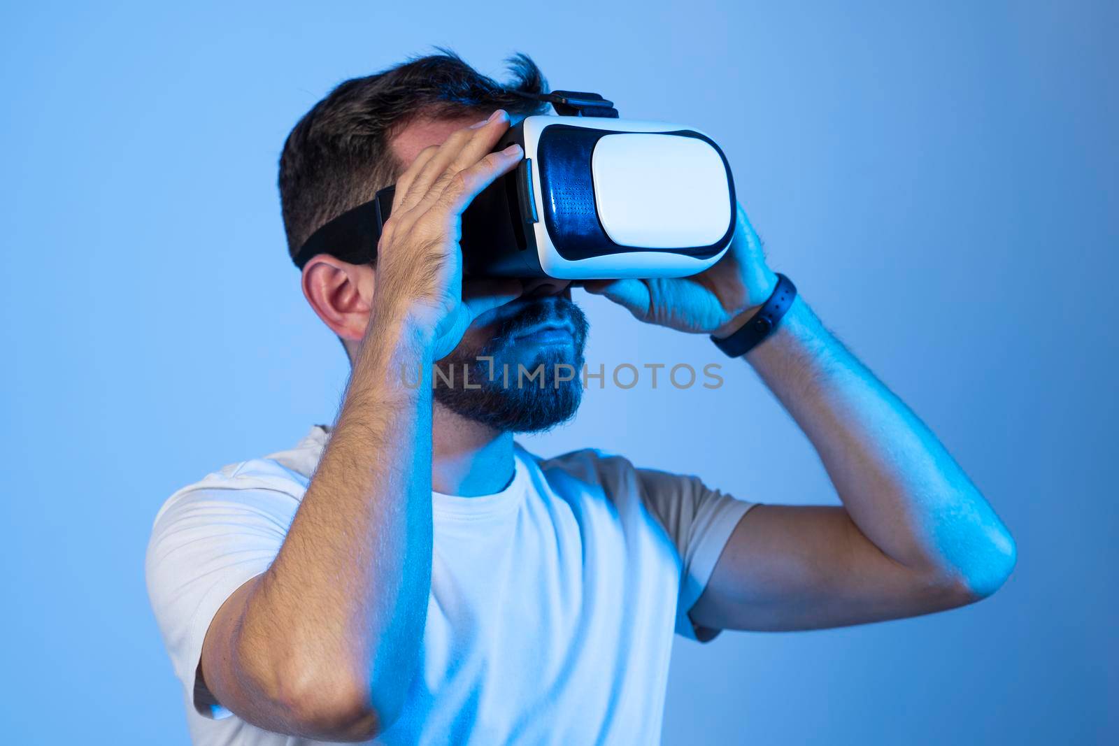 Young bearded man wearing virtual reality VR glasses goggles diving into the metaverse. Future technology concept. by vovsht