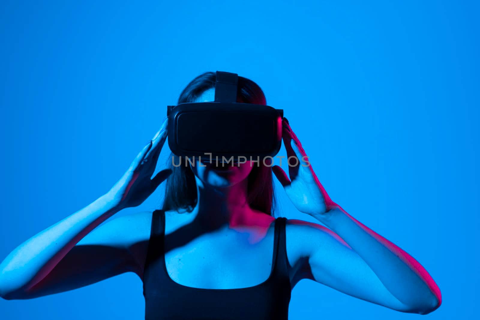 Young attractive curious woman wearing VR goggles and enjoying amazing experience playing and having fun in virtual reality video game