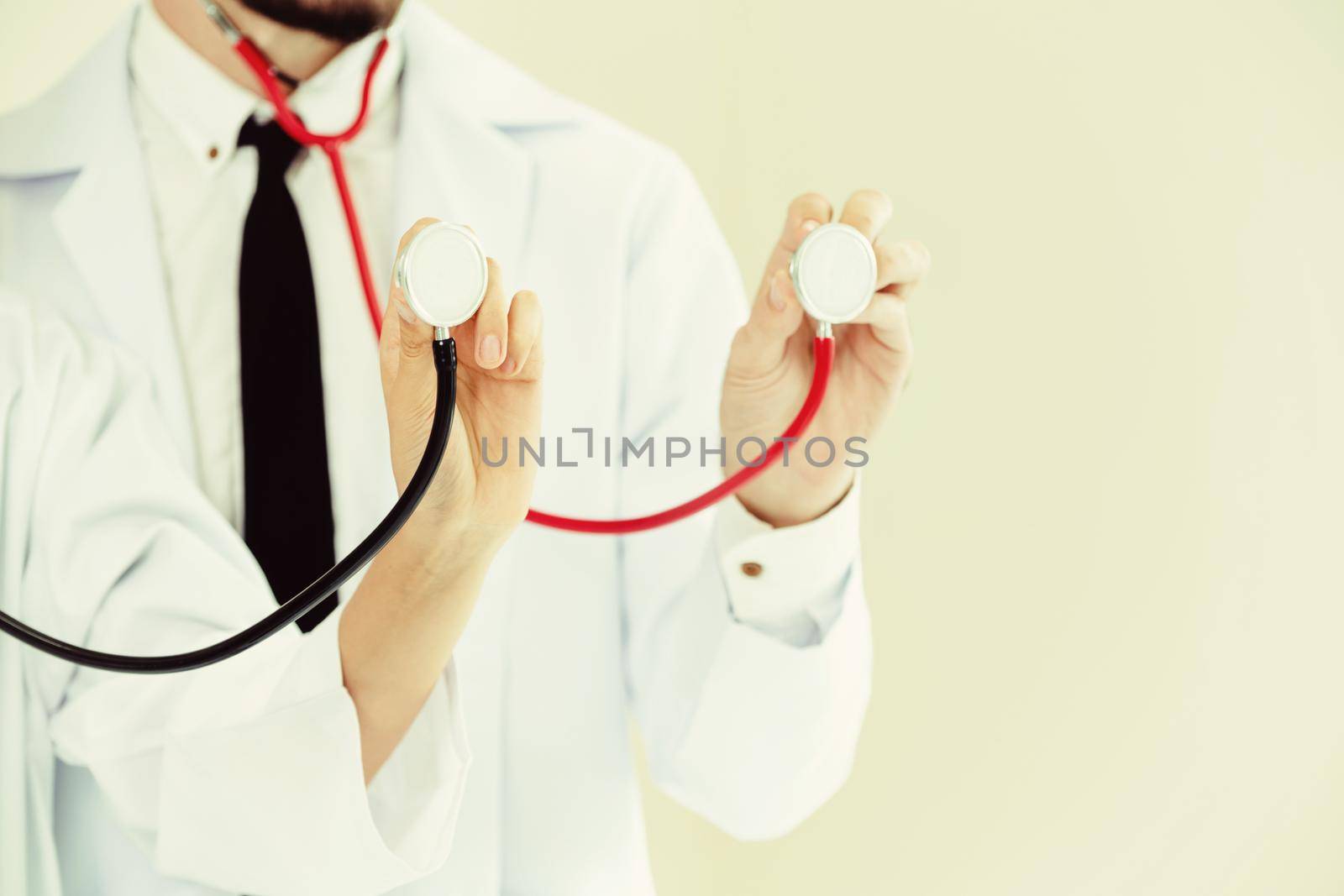 Close up shot of two doctors pointing stethoscope at copy space. Selective focus at front doctors hand.
