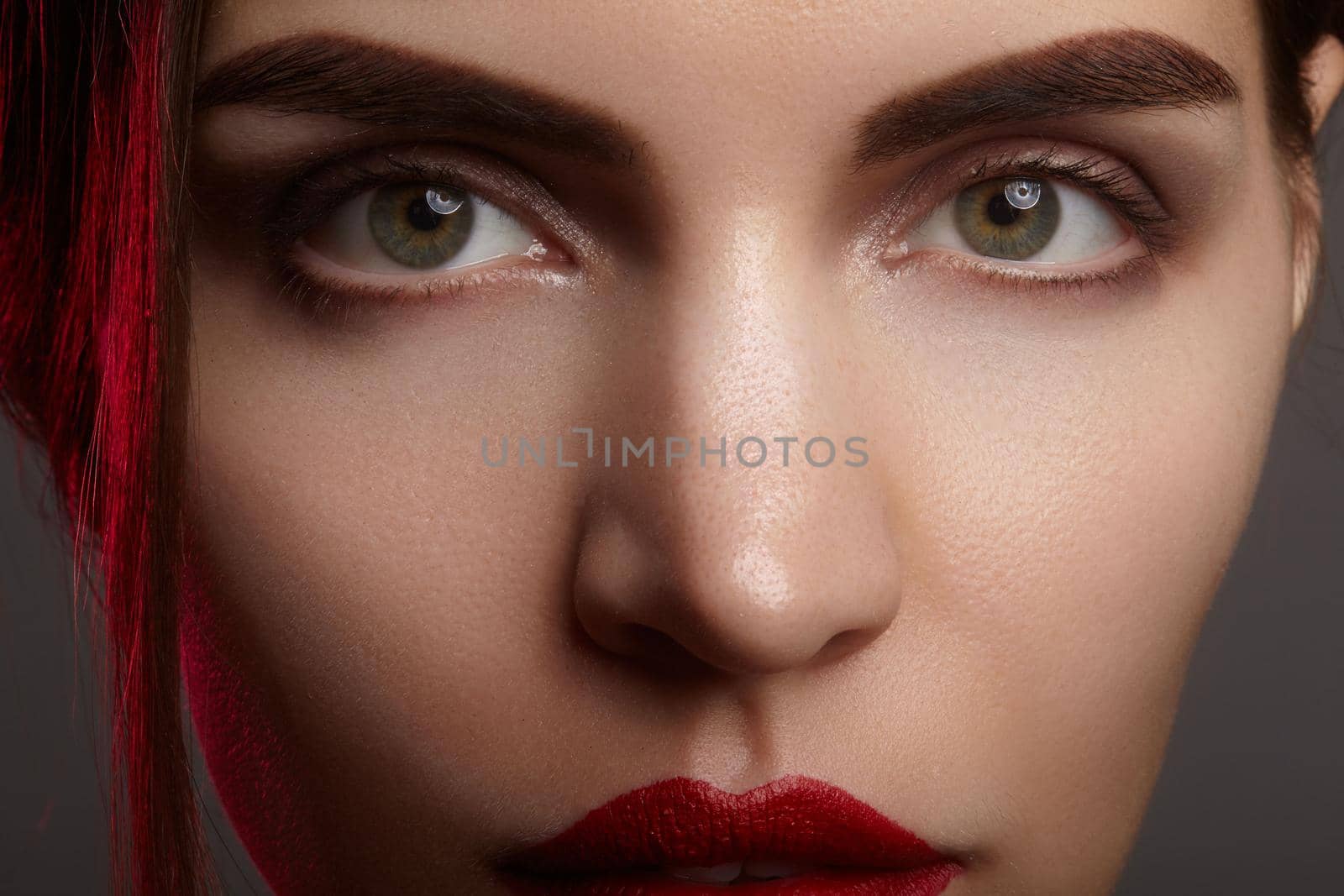 Closeup portrait with of beautiful woman face. Red color of fashion lip makeup, clean shiny skin and strong eyebrows. Makeup and cosmetic. Beauty style