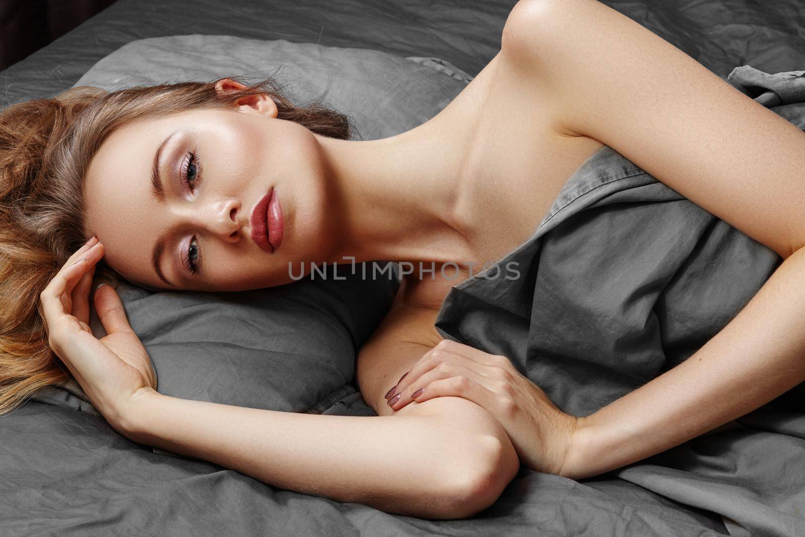 Beautiful Woman Sleeping while lying in Bed with Comfort. Sweet dreams. Sexy model relaxing on grey sheets by MarinaFrost