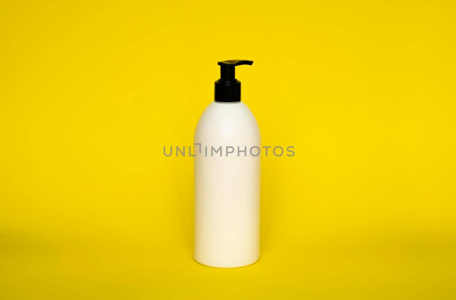 Large white plastic bottle with pump dispenser on yellow background. Mock up template for design