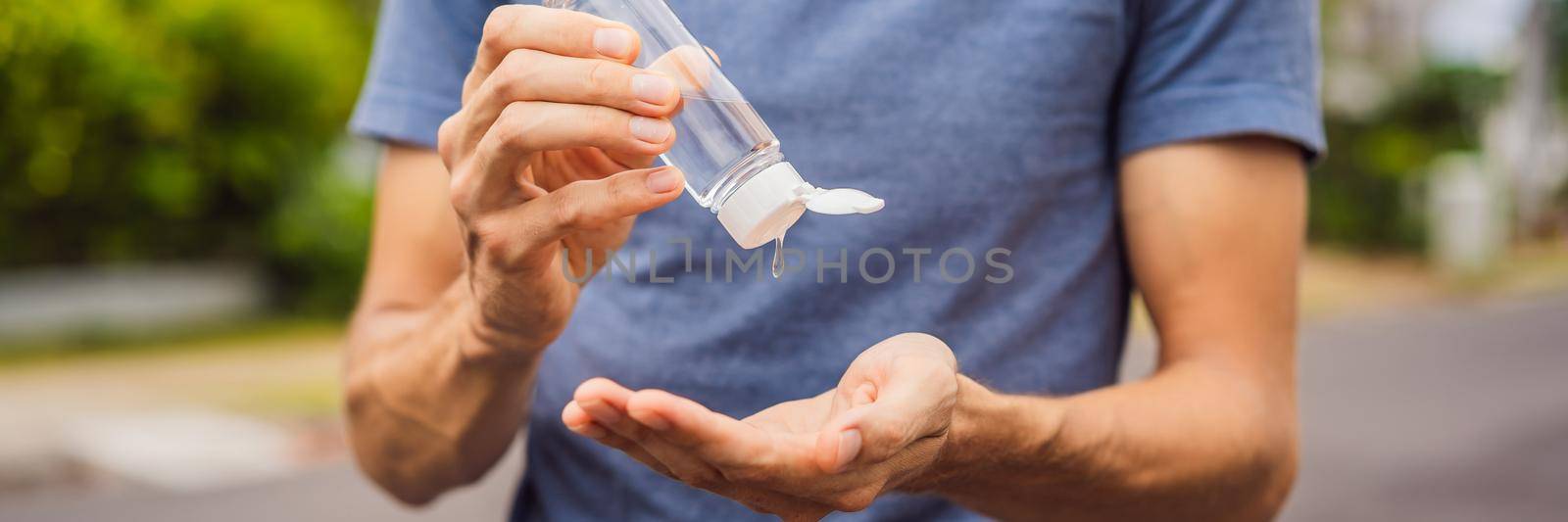 Man in a small town in a medical mask uses a sanitizer because of a coronovirus epidemic. BANNER, LONG FORMAT