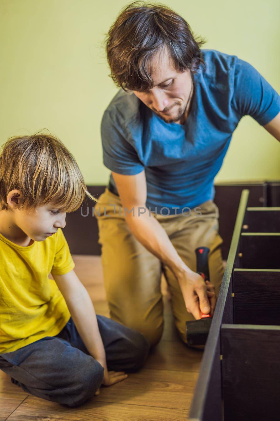 Father and son assembling furniture. Boy helping his dad at home. Happy Family concept.