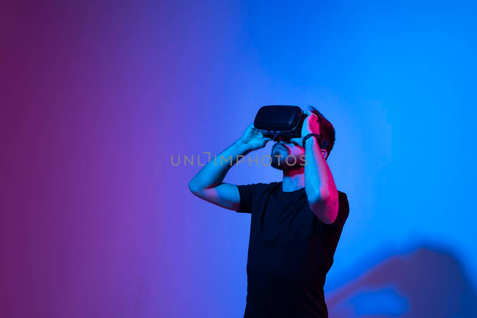 Bearded man in virtual reality headset communicate with a friends in a metaverse. Young man playing a vr video game