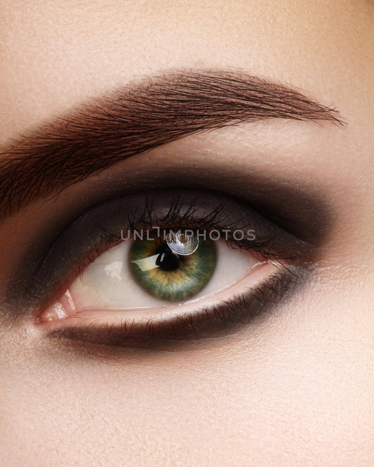 Beautiful macro photo of woman eye with black smoky makeup. Perfect shape eyebrows. Cosmetics and make-up by MarinaFrost