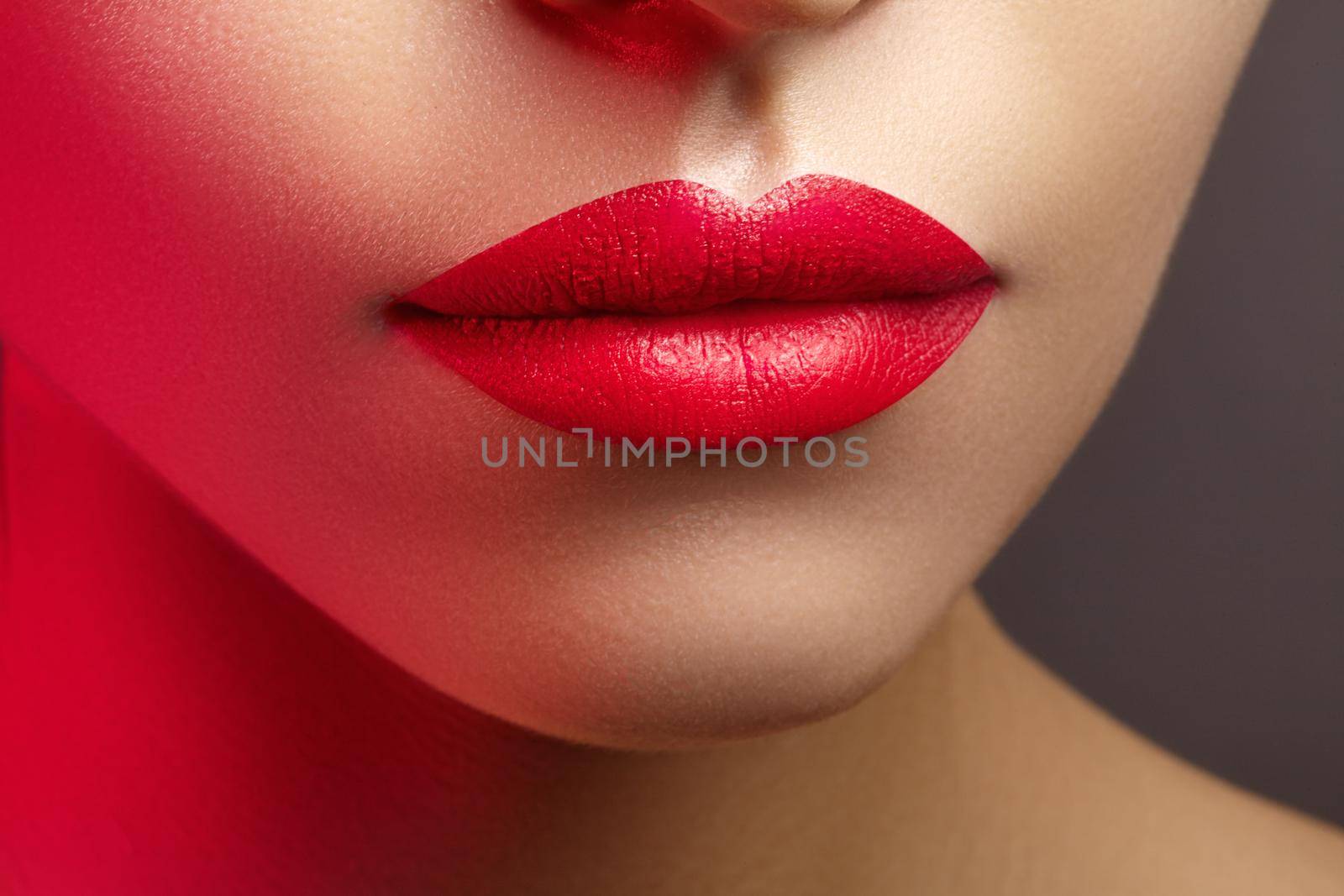 Cosmetics, makeup. Bright lipstick on lips. Closeup of beautiful female mouth with red lip makeup. Clean skin model by MarinaFrost