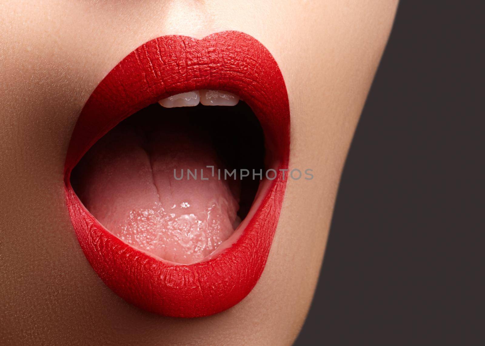 Cosmetics, makeup. Bright lipstick on lips. Closeup of beautiful female mouth with red lip makeup. Clean skin model by MarinaFrost