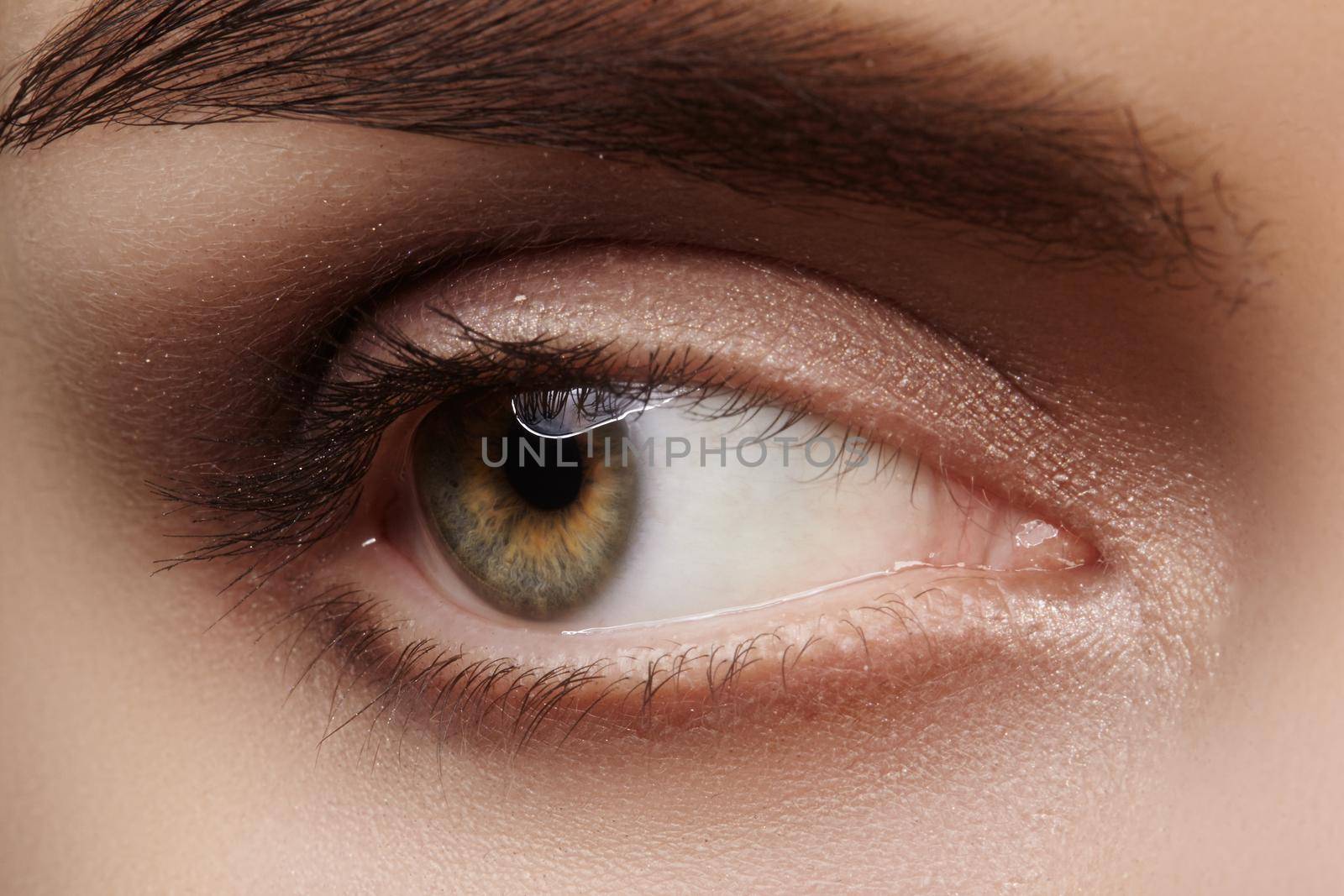 Close-up macro beautiful female eye with perfect shape eyebrows. Clean skin, fashion natural smoky make-up. Good vision by MarinaFrost