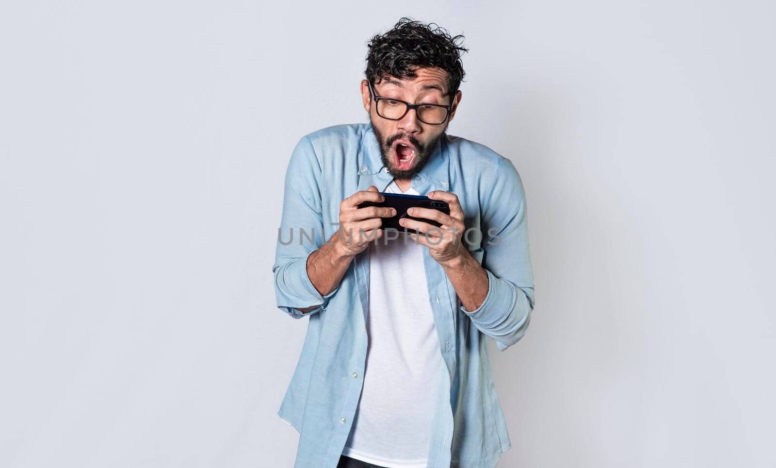 Man holding cell phone horizontally, Guy gasping and playing games on his smartphone