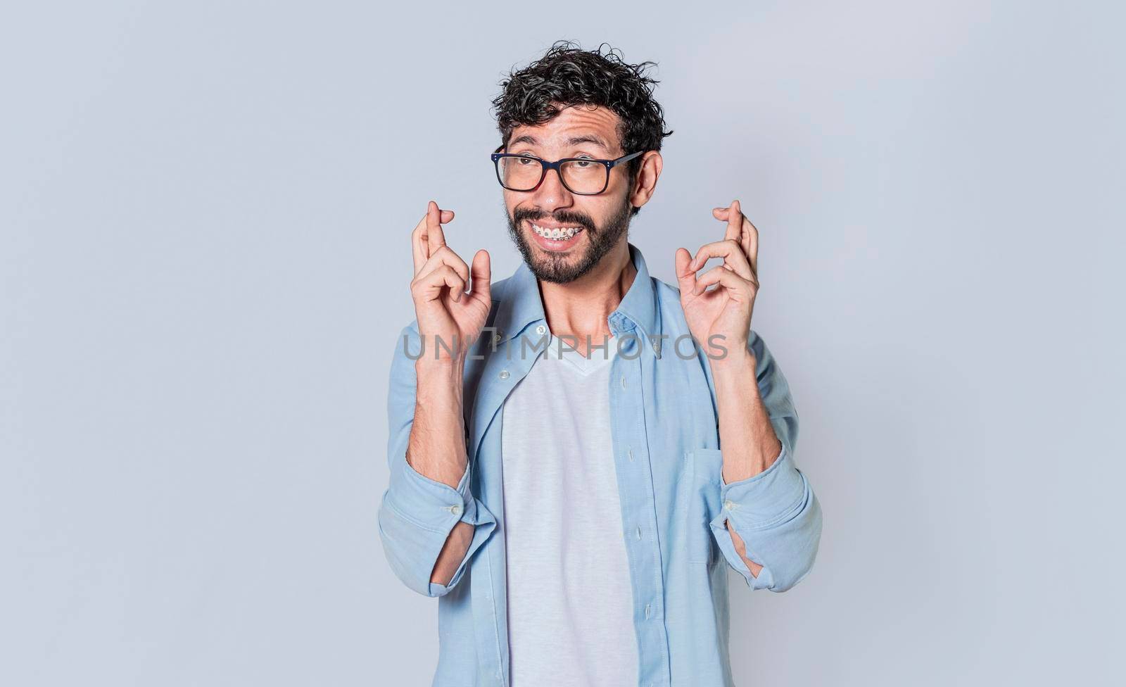 Happy man making a wish, latin guy crossing his fingers making a wish