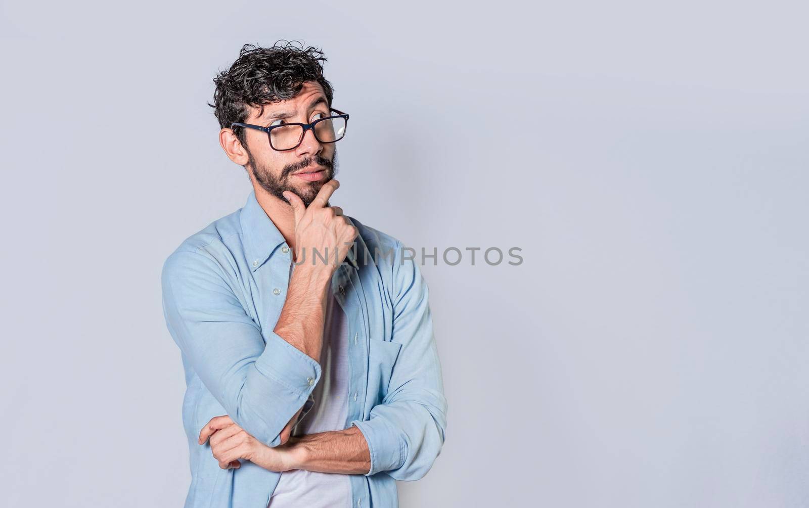 young man wondering with his hand on his chin on an isolated background, a guy thinking with his hand on his chin.