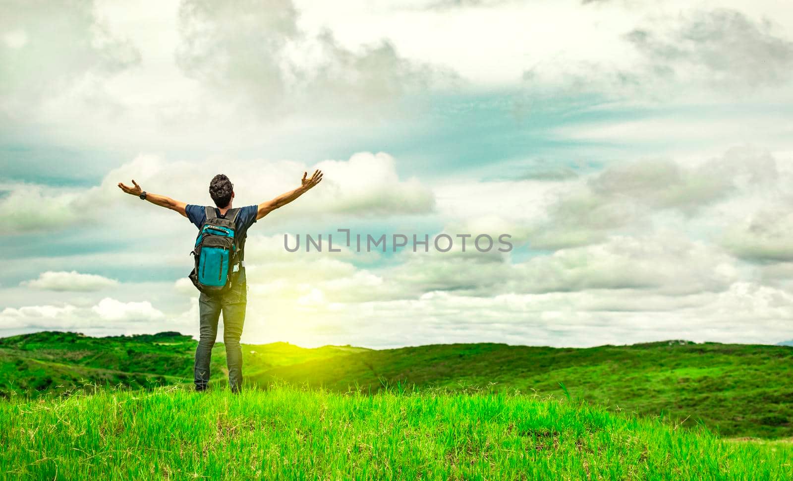 backpacker man in the field spreading his hands, concept of successful man spreading his hands