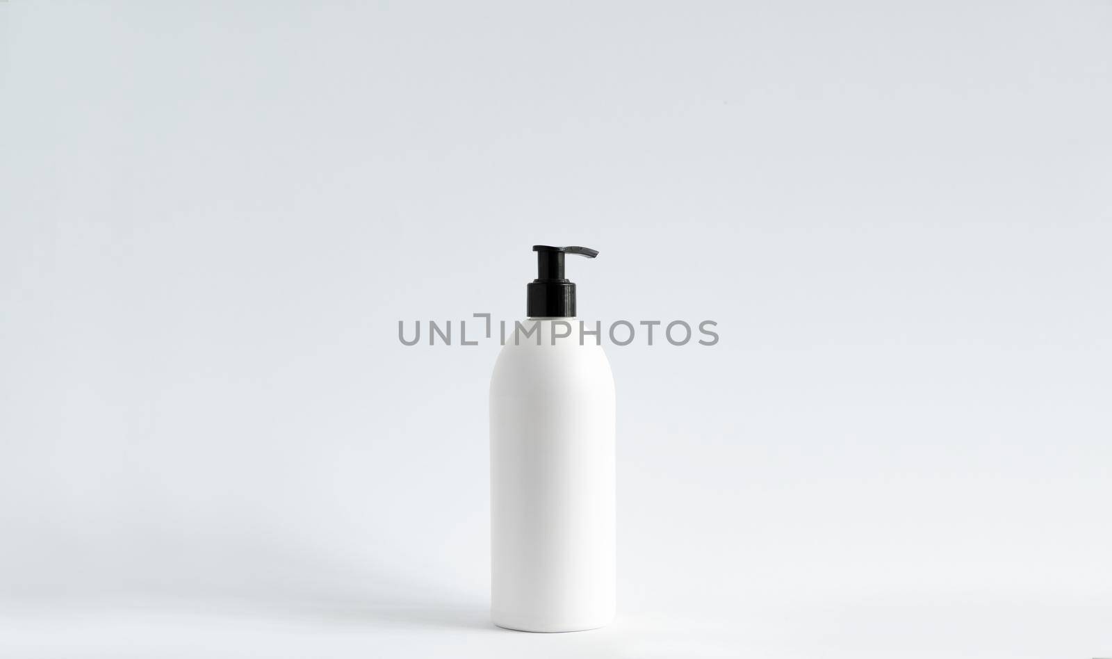 White plastic bottle with shampoo, conditioner or shower gel on a white background. Mock up template for design. by vovsht