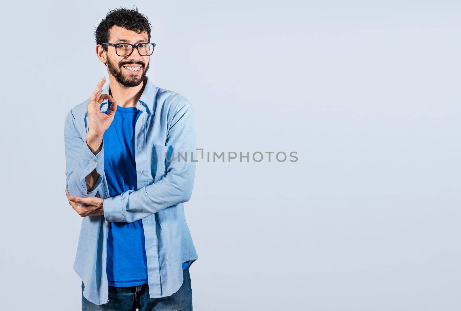 Man gesturing everything is ok, young man making ok gesture, Smiling man showing ok gesture looking at camera, expression of everything is fine.