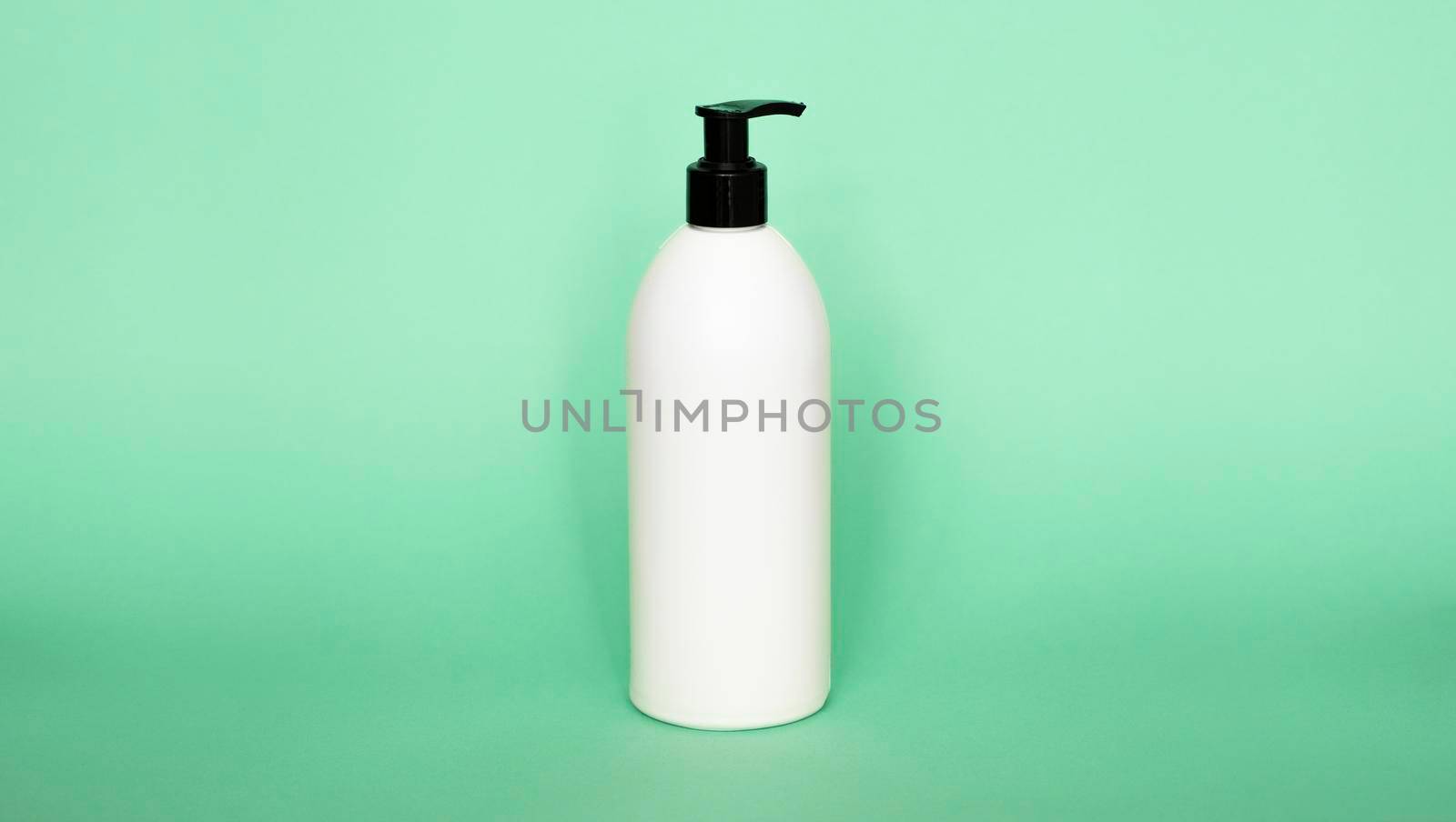 White plastic bottle with shampoo, conditioner or shower gel on a green background. Mock up template for design