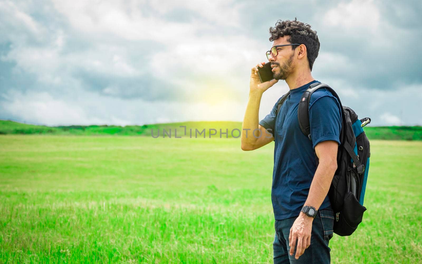 Man calling by cell phone, young man in the field calling by cell phone