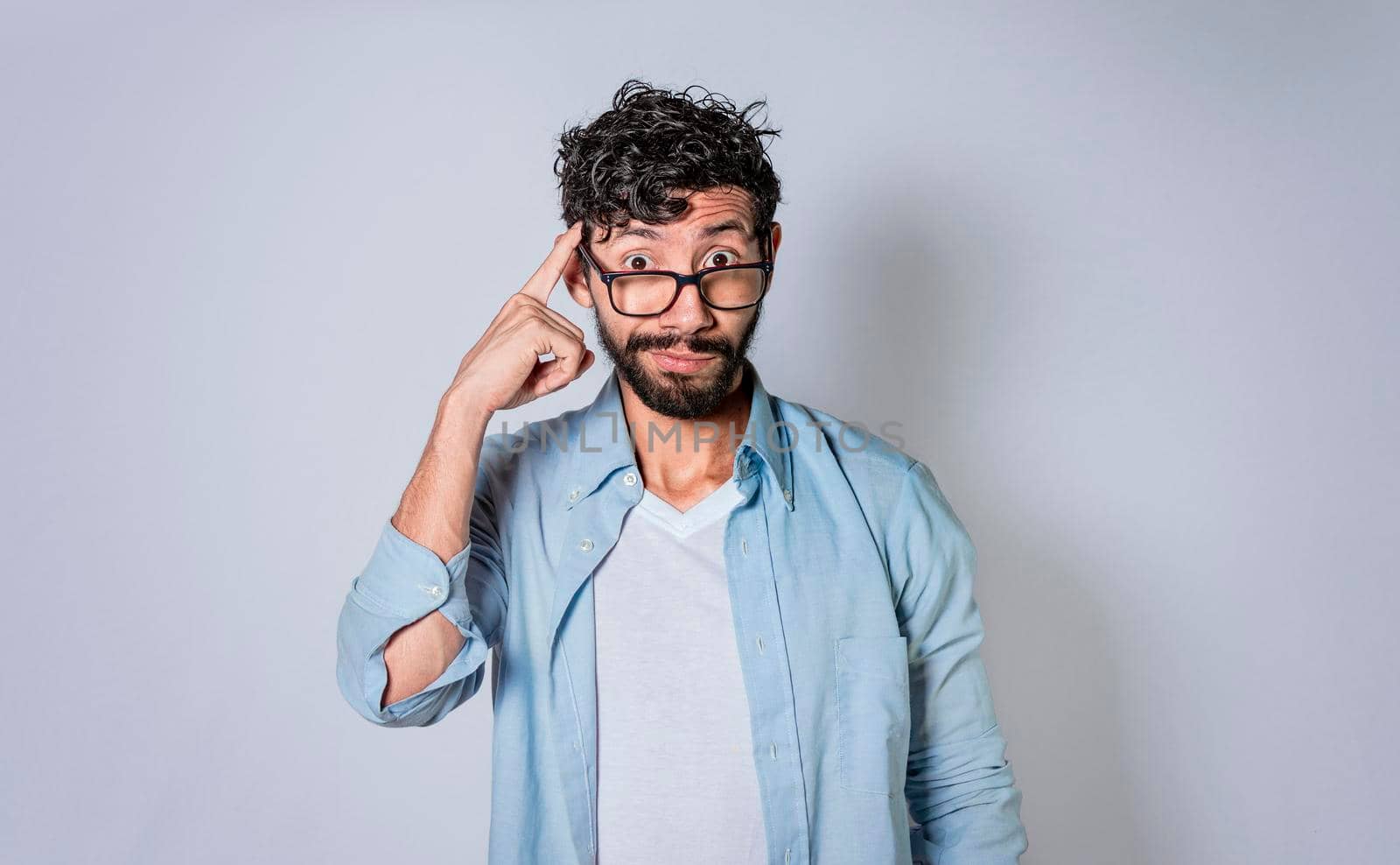 young man wondering with his finger on isolated background, A guy thinking with his finger on his head.