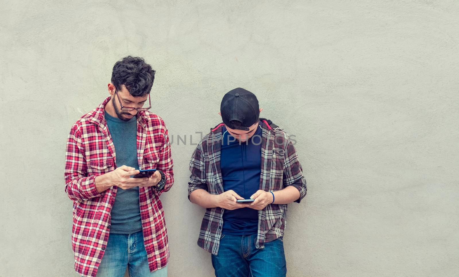 Two guys checking their cell phones, Smiling attractive young people checking their cell phones, Two guys with their cell phones