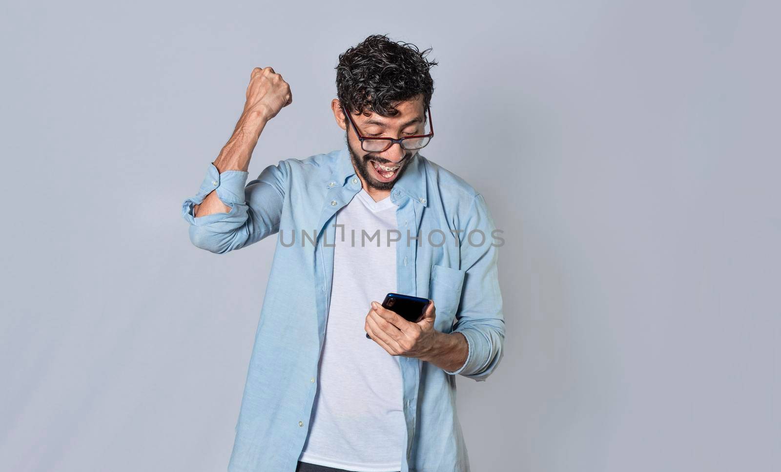 Happy man holding a smartphone and celebrating, Excited guy looking at his smartphone