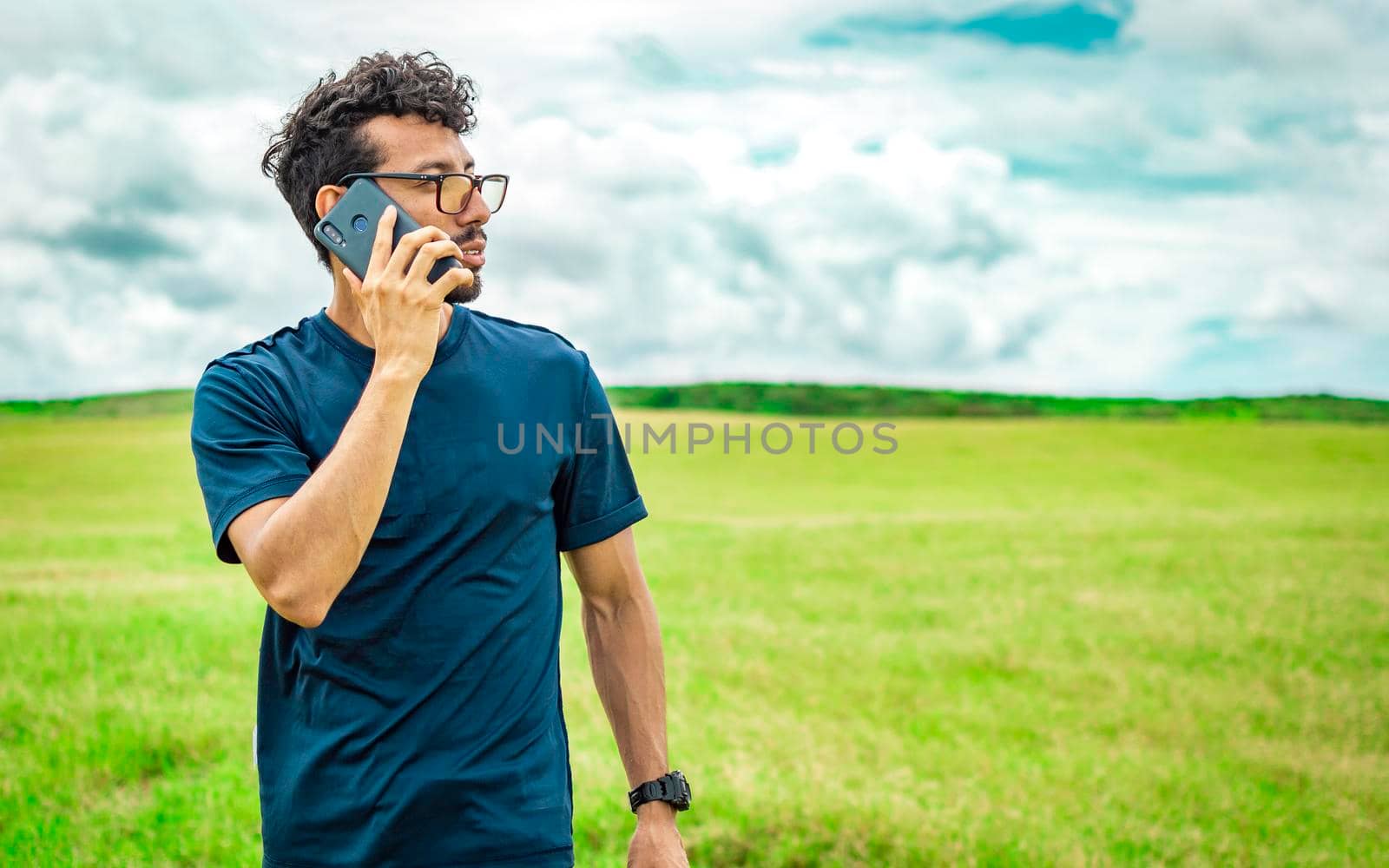 Man calling by cell phone, young man in the field calling by cell phone