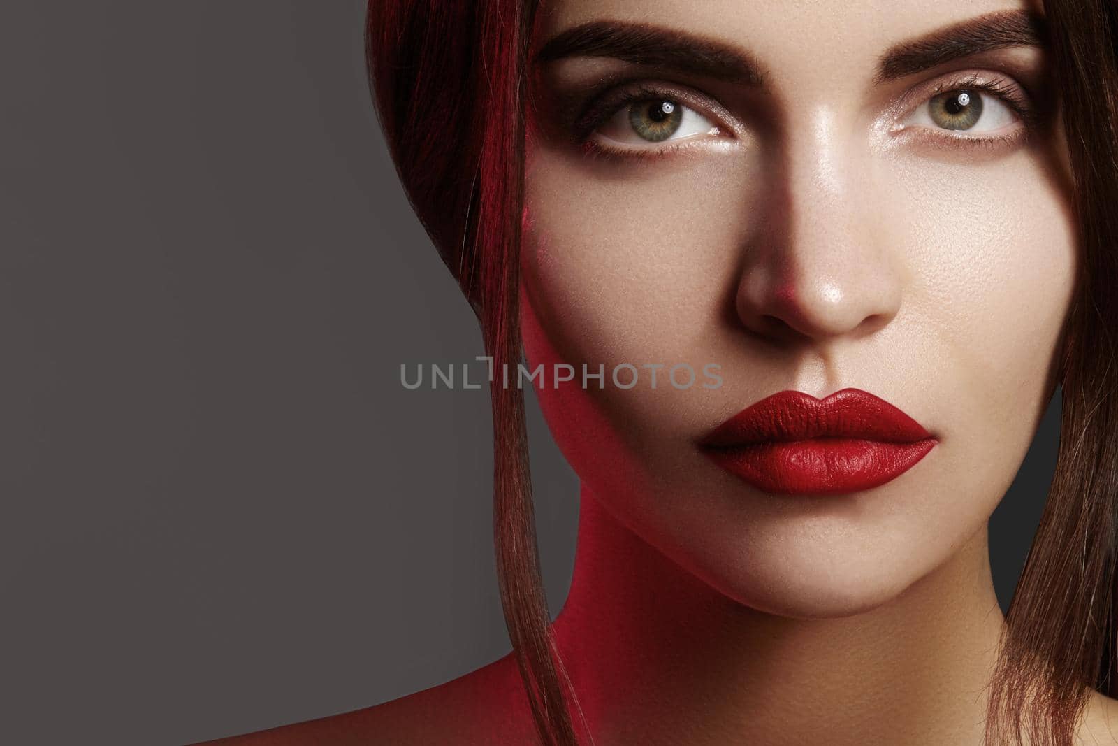 Closeup portrait with of beautiful woman face. Red color of fashion lip makeup, clean shiny skin and strong eyebrows. Makeup and cosmetic. Beauty style