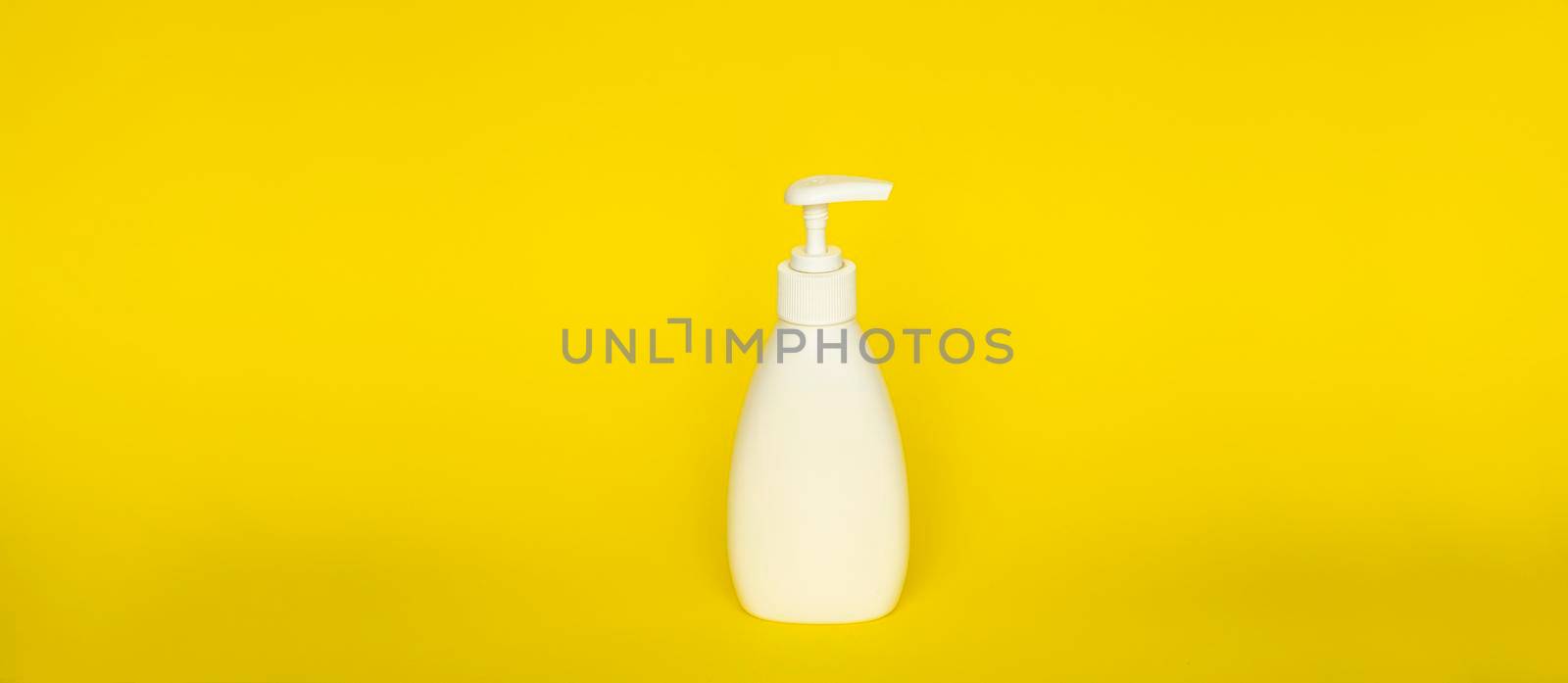 Large white plastic bottle with pump dispenser on yellow background. Mock up template for design
